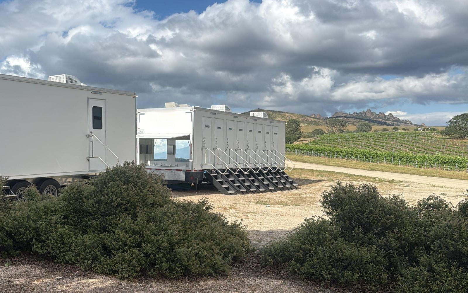 8-stall shower trailer with its outdoor sink counter open beside a restroom trailer at a vineyard event, The Lavatory NorCal