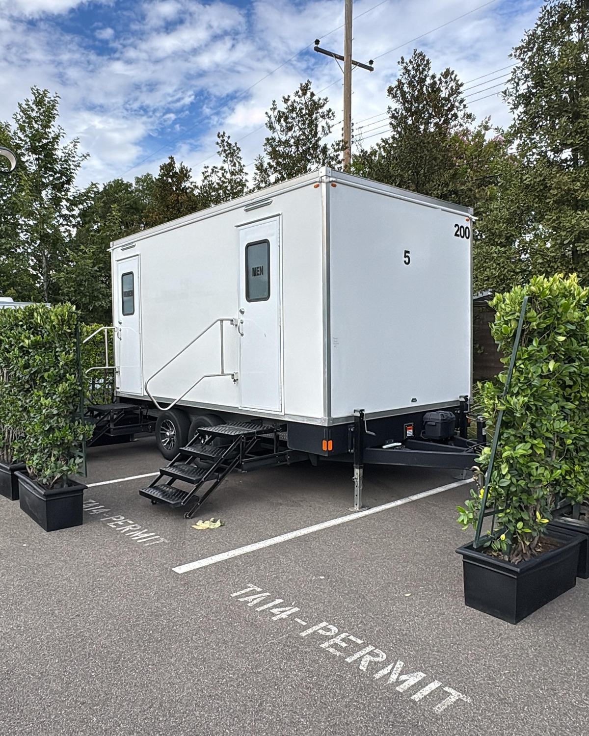 Restroom trailer screened by potted hedges in a corporate campus parking lot, The Lavatory NorCal