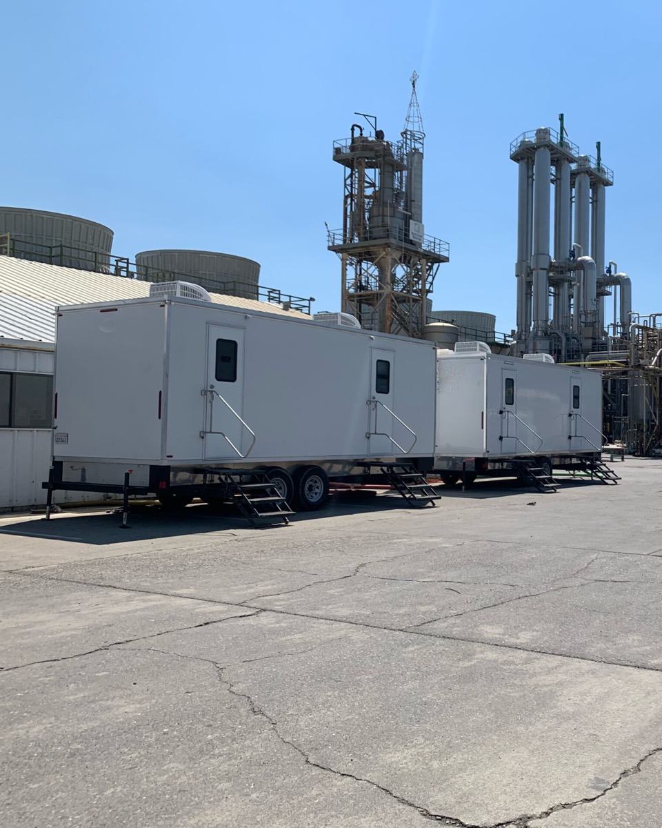 Two restroom trailers set beside a processing plant for crews on long shifts, The Lavatory NorCal