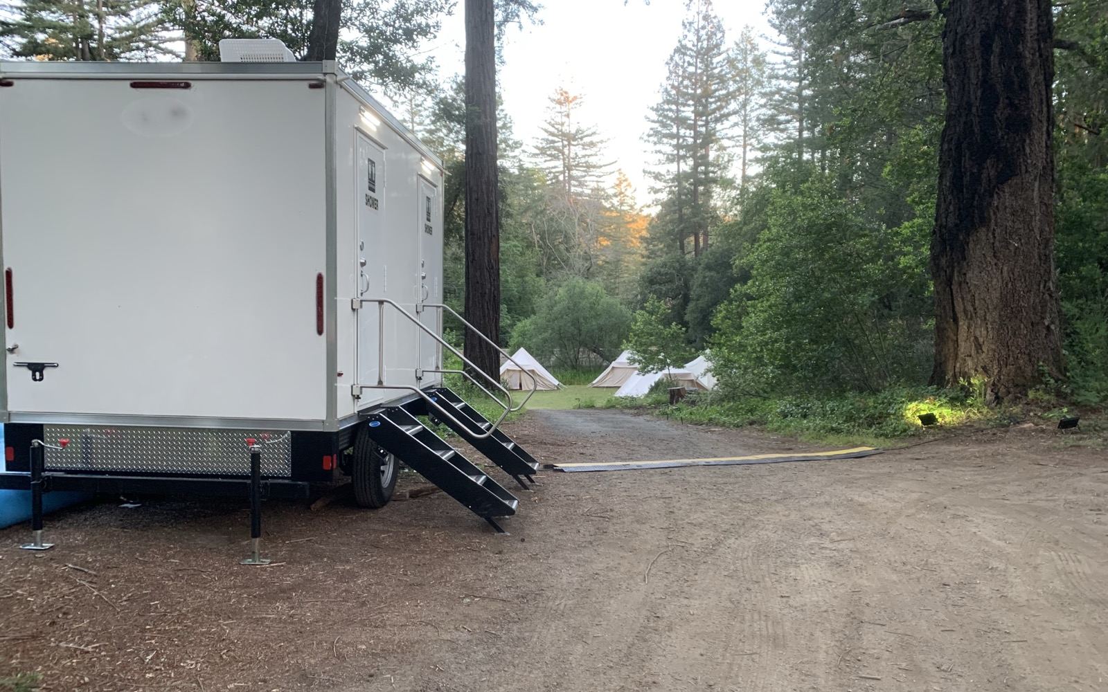 Shower and restroom combo trailer in a redwood grove at a glamping camp with canvas tents, The Lavatory NorCal