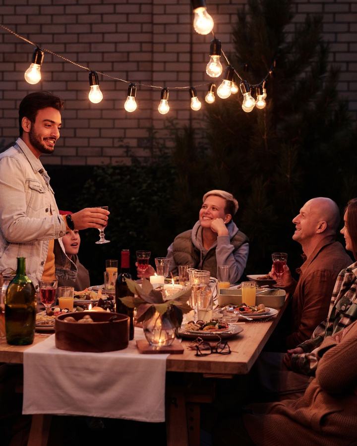 Family dinner party under string lights in a backyard, a use case for The Lavatory NorCal restroom trailers