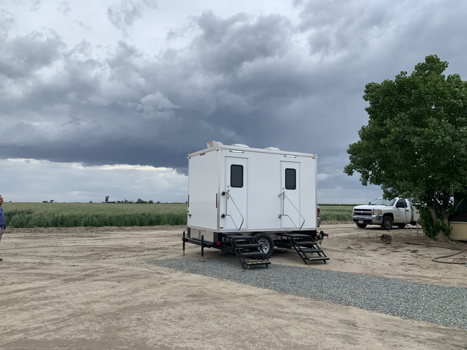 2-stall bathroom trailer beside a farm field under dark storm clouds in the East Bay, The Lavatory NorCal