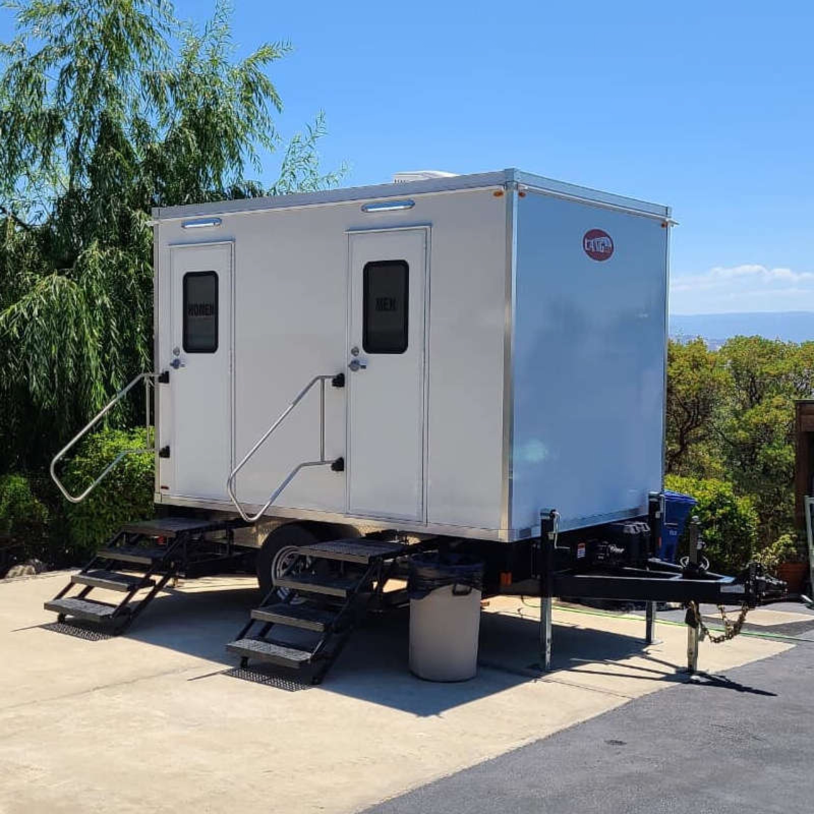 2-stall portable bathroom trailer with women's and men's doors and folding stairs on a sunny Bay Area hillside lot, The Lavatory NorCal