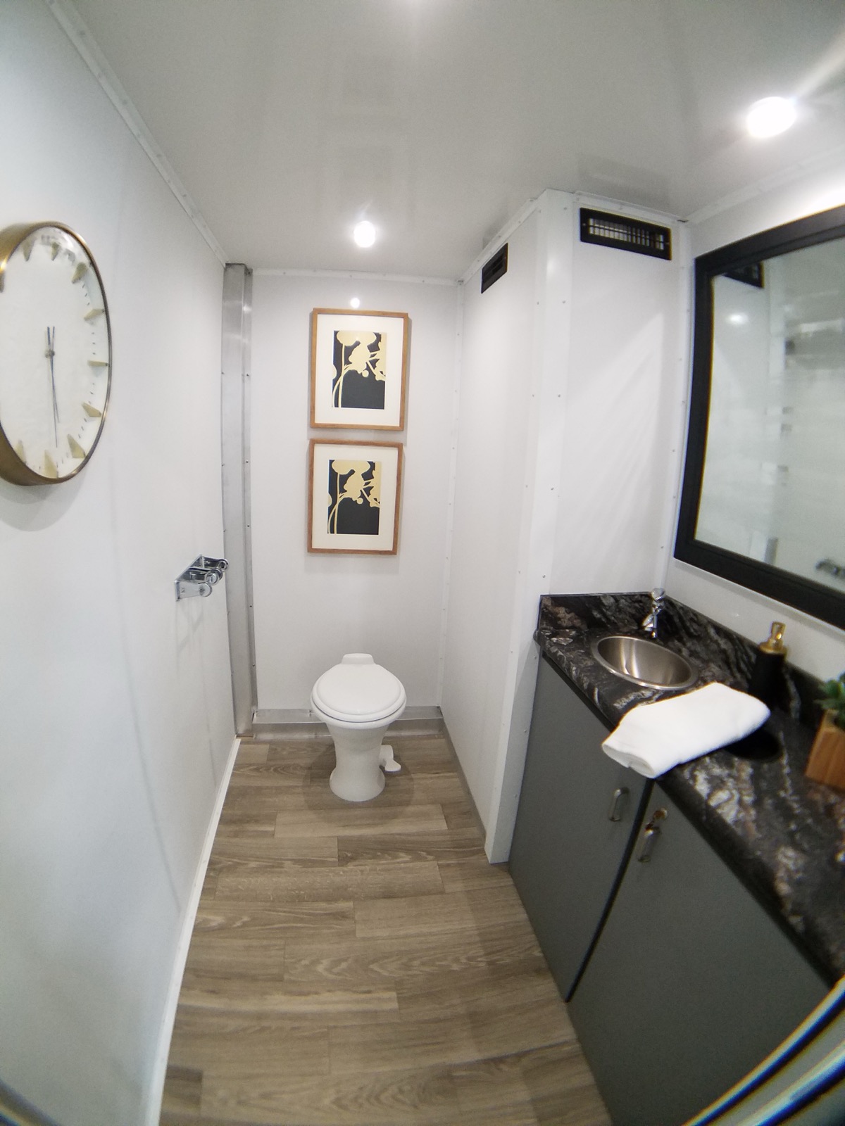 Women's room in a 2-stall restroom trailer with china toilet, stone-look vanity and gold wall clock, The Lavatory NorCal