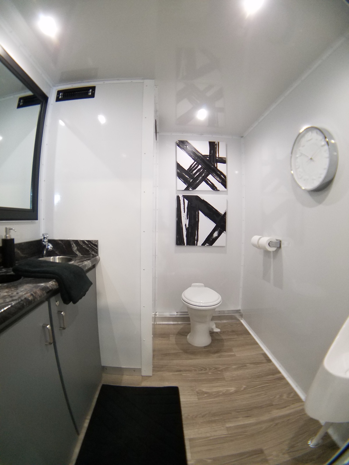 Men's room inside a 2-stall bathroom trailer with a china toilet, vanity and modern art, The Lavatory NorCal