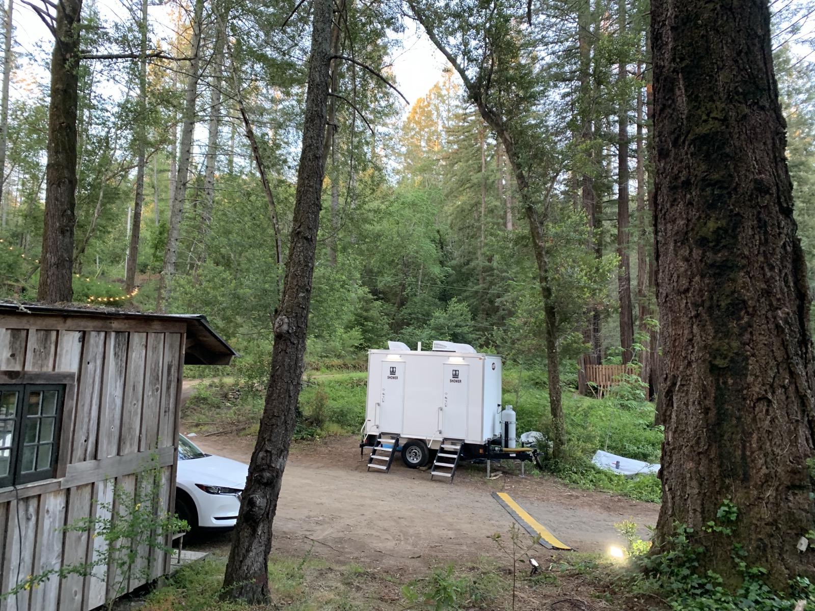 2-stall combo trailer set among tall redwoods beside a rustic cabin in the hills, The Lavatory NorCal