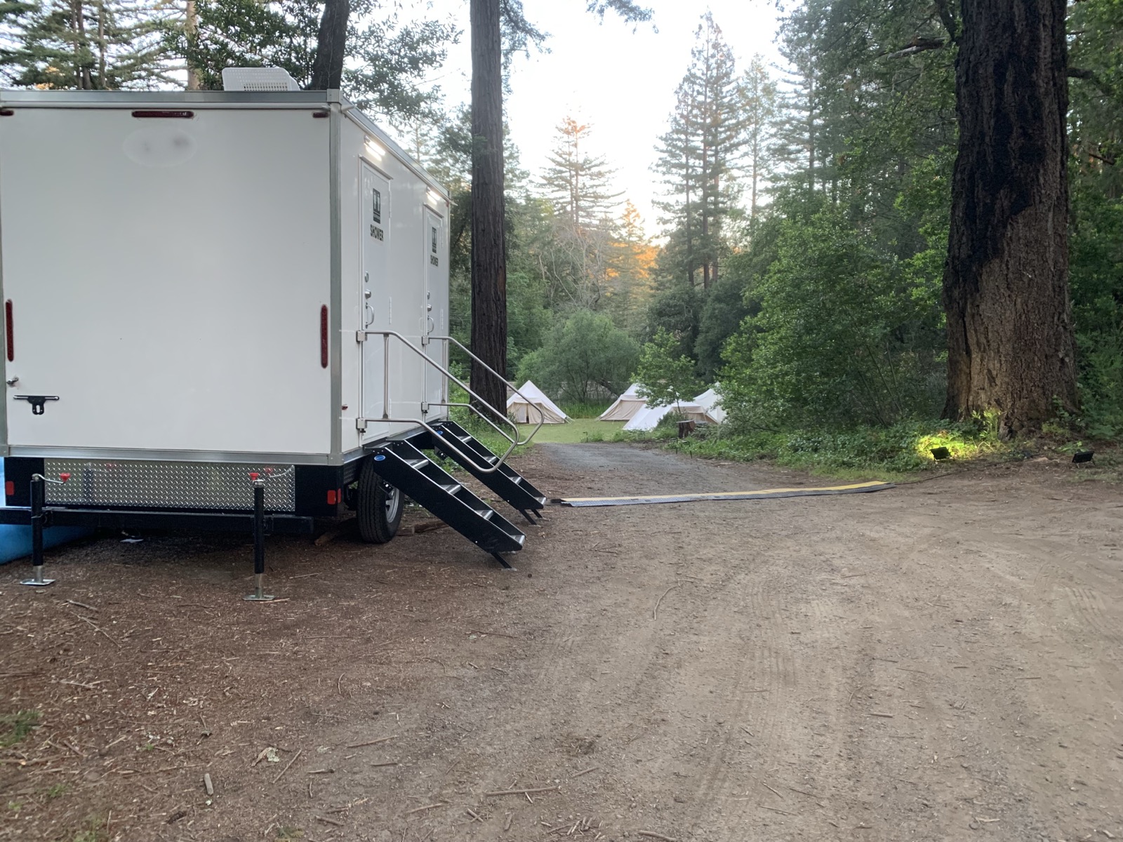 2-stall combo trailer set up at a redwood glamping camp beside canvas tents, The Lavatory NorCal