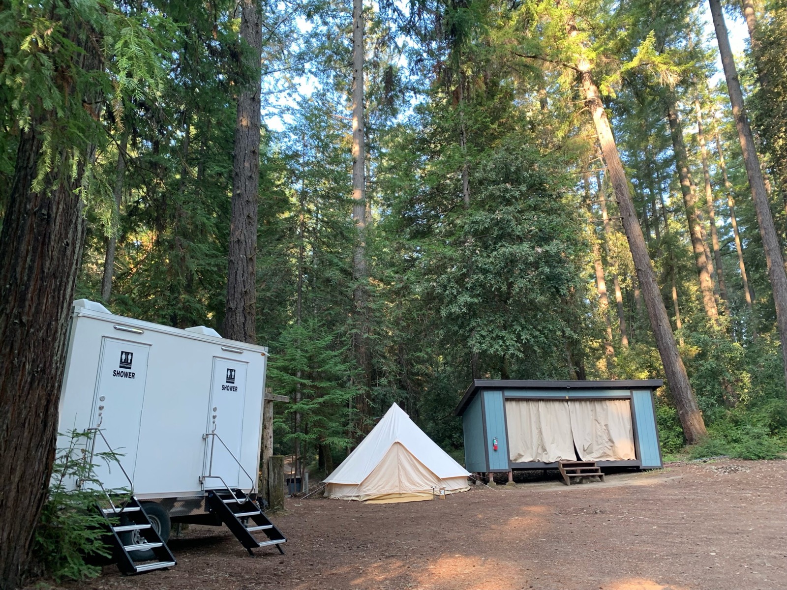 Shower trailer beside a canvas bell tent at a redwood glamping camp, The Lavatory NorCal