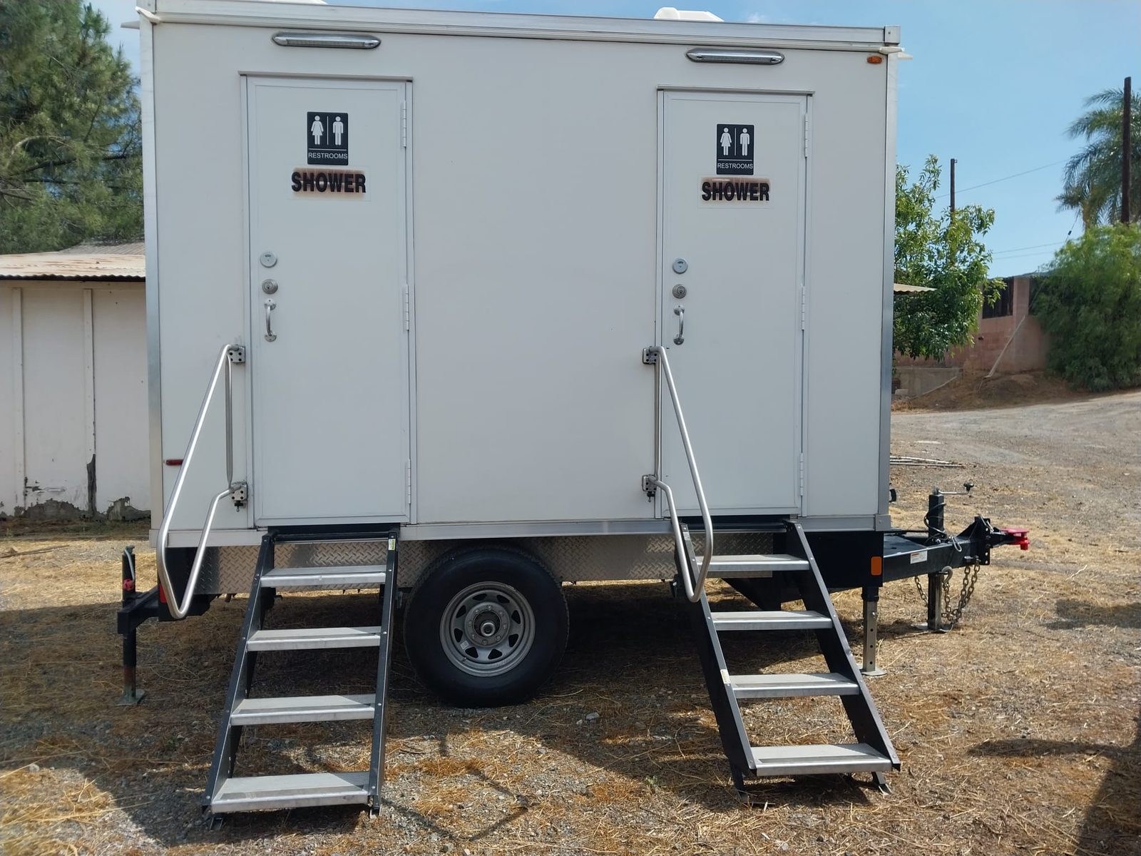 2-station shower and restroom combo trailer set up in a dry rural yard, The Lavatory NorCal