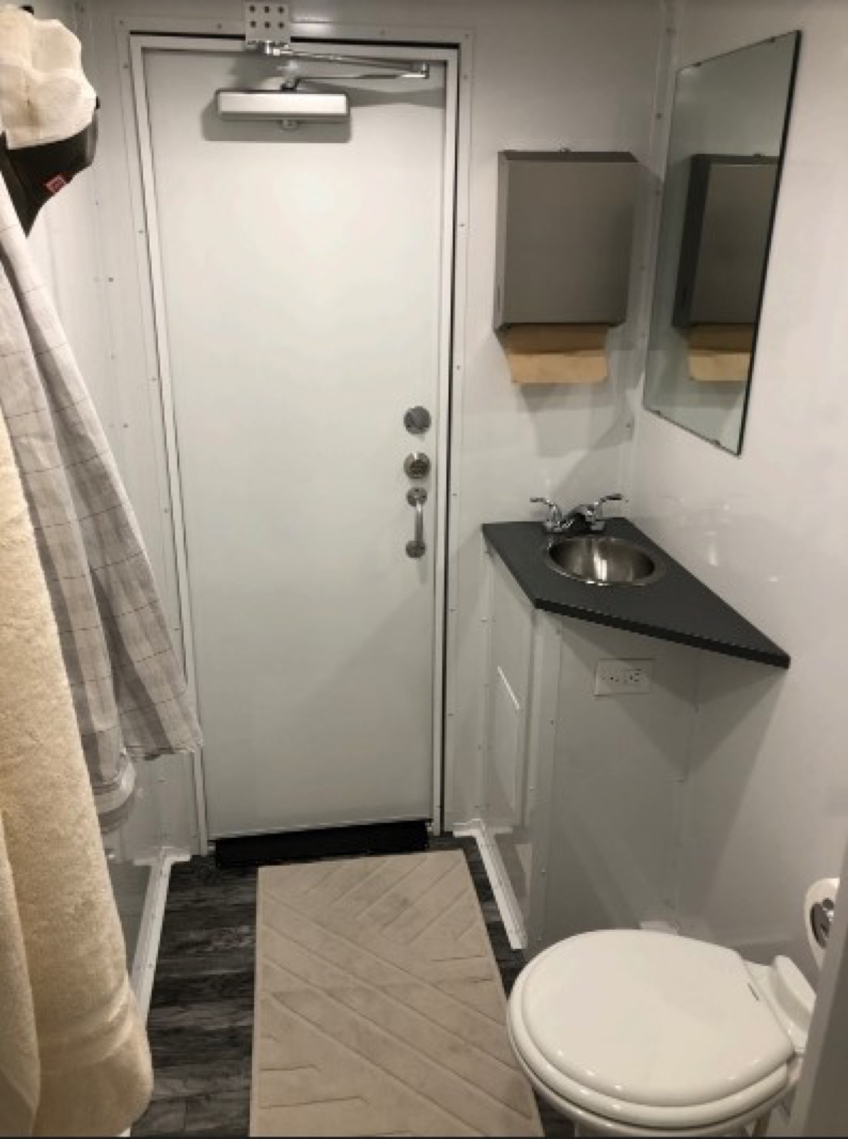 Private room inside a 4-stall combo trailer with a corner sink and toilet next to the laundry room, The Lavatory NorCal