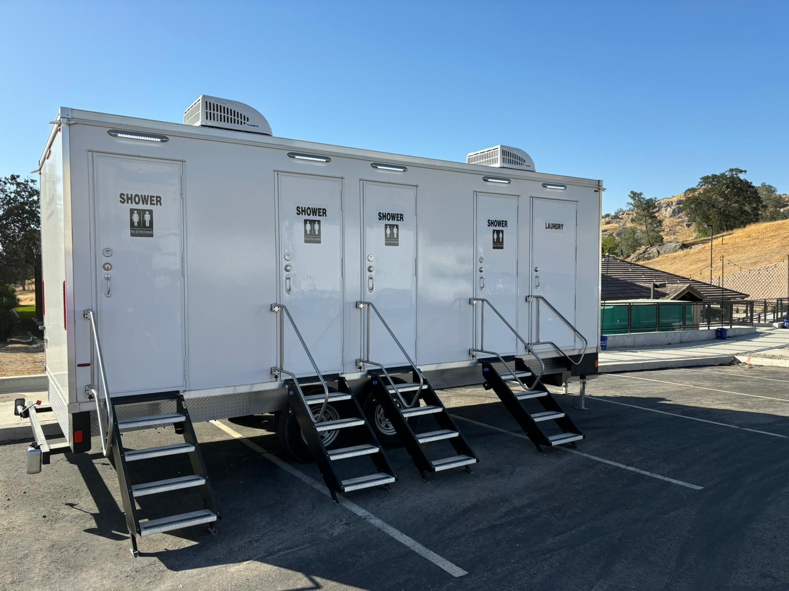 4-station shower, restroom and laundry combo trailer in a parking lot with golden foothills behind, The Lavatory NorCal