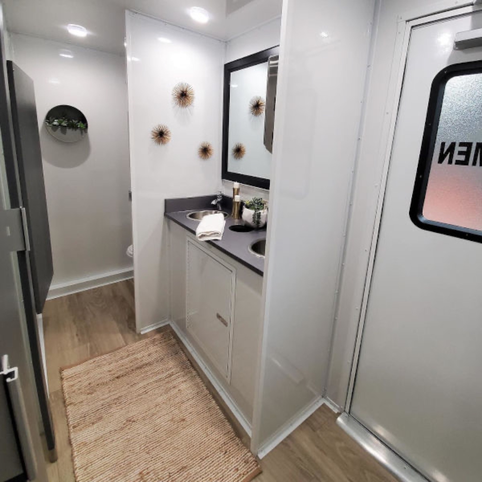 Double vanity and private stall doors inside a large temporary restroom trailer kept clean on a long rental, The Lavatory NorCal