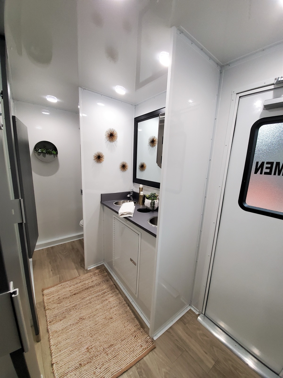 Women's side of a 5-stall luxury restroom trailer with a double sink vanity and framed mirror, The Lavatory NorCal