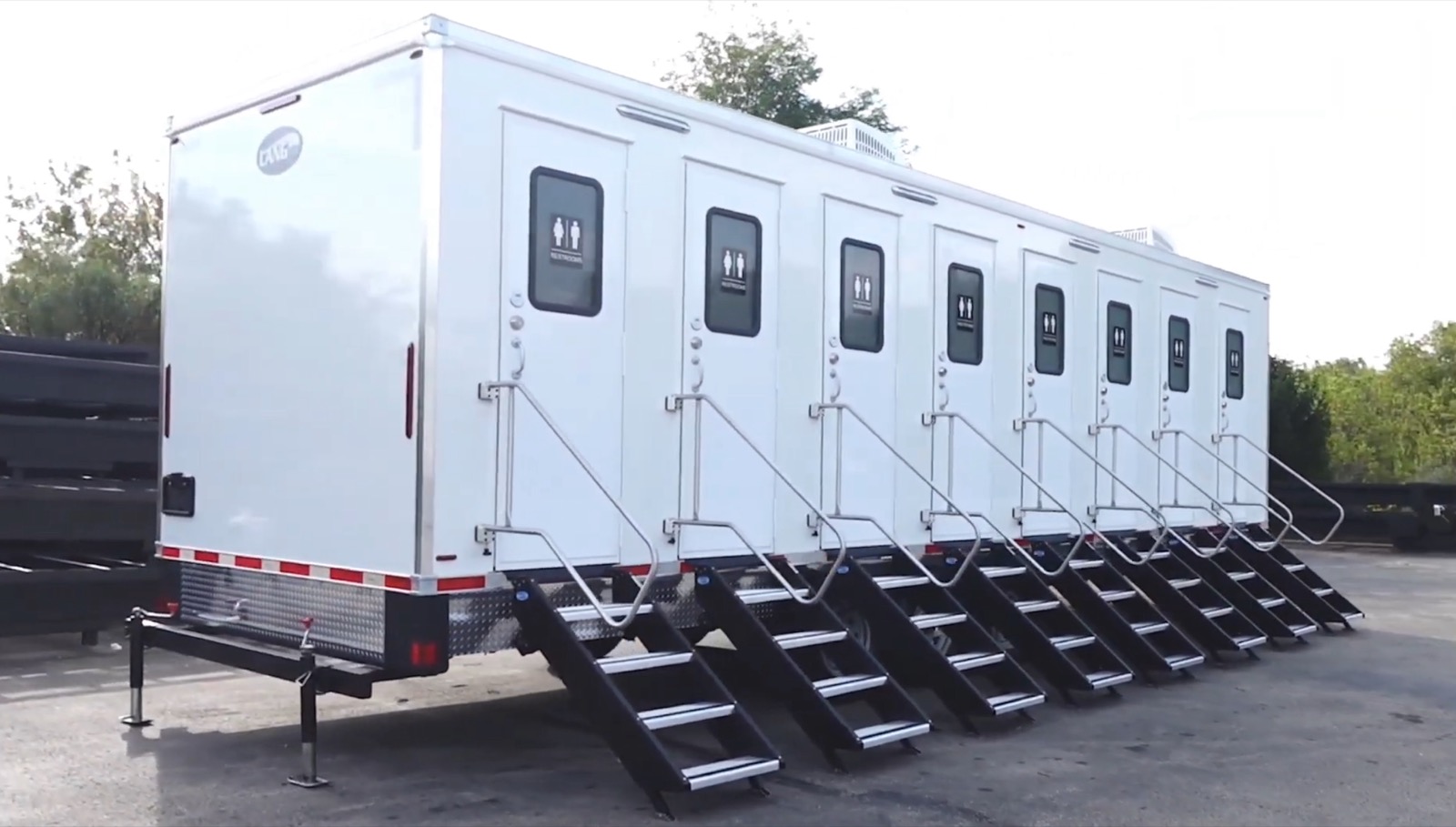 Angled view of the 8-stall private bathroom trailer showing stairs and railings at each of the eight doors, The Lavatory NorCal