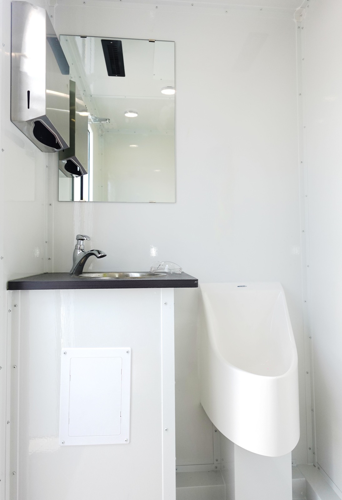 Sink, mirror and urinal inside one private room of an 8-stall bathroom trailer, The Lavatory NorCal