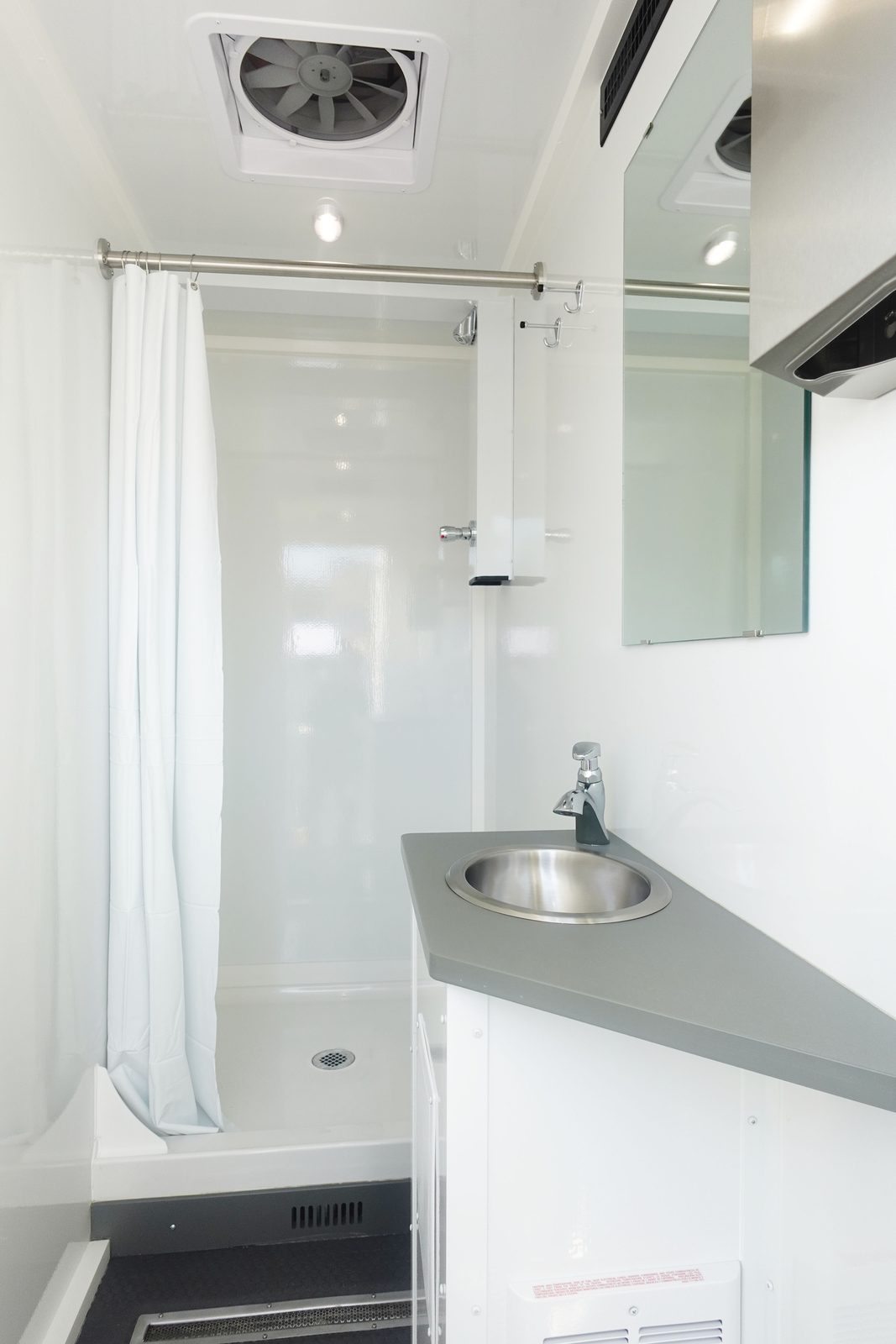 Private shower cabin in the 8-stall shower trailer with curtain, vanity sink, mirror and exhaust fan, The Lavatory NorCal