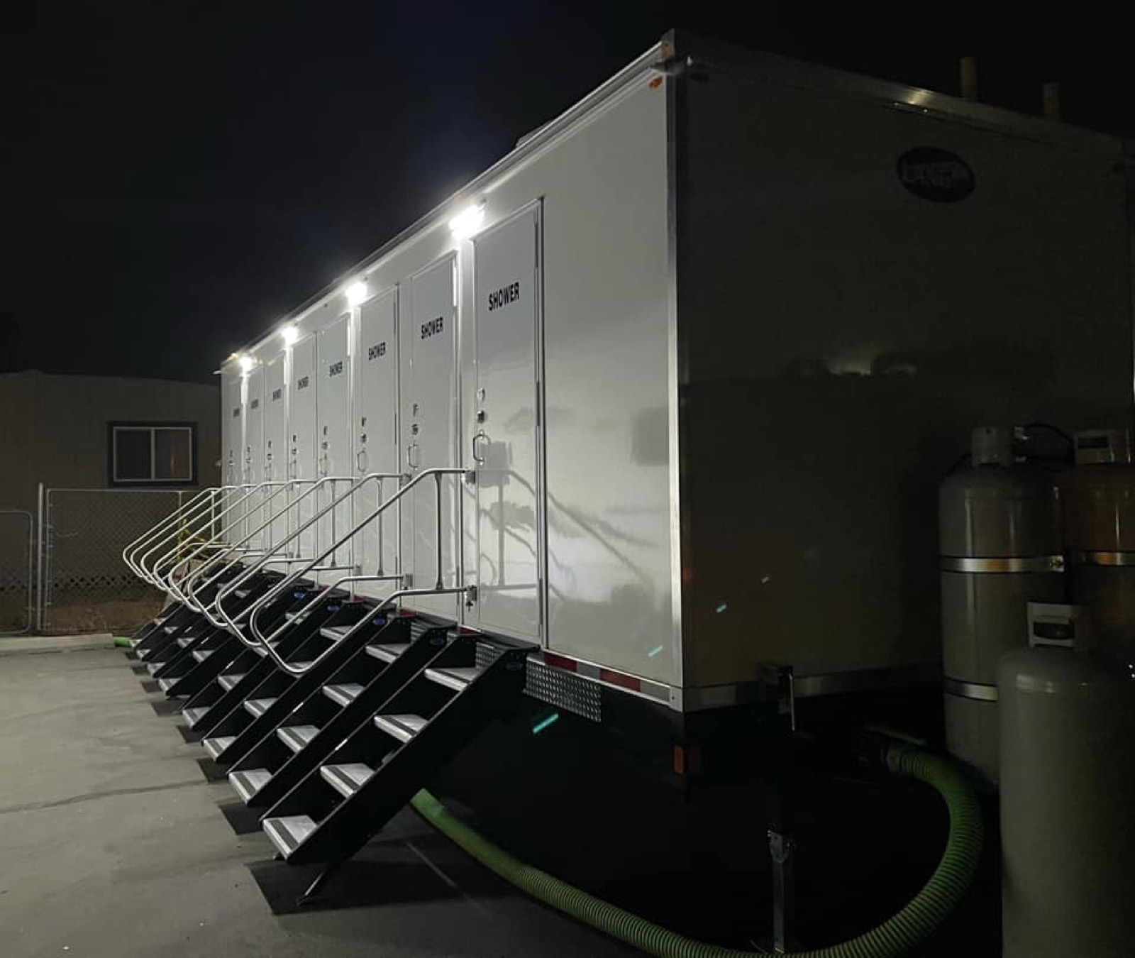 8-stall shower trailer lit up at night during a fire response, with stairs at each shower door, The Lavatory NorCal