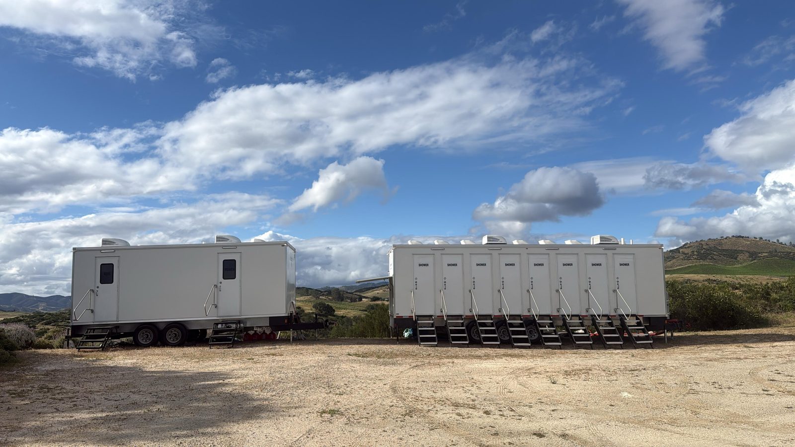 8-stall shower trailer next to a bathroom trailer on a dirt pad at a hillside vineyard, The Lavatory NorCal