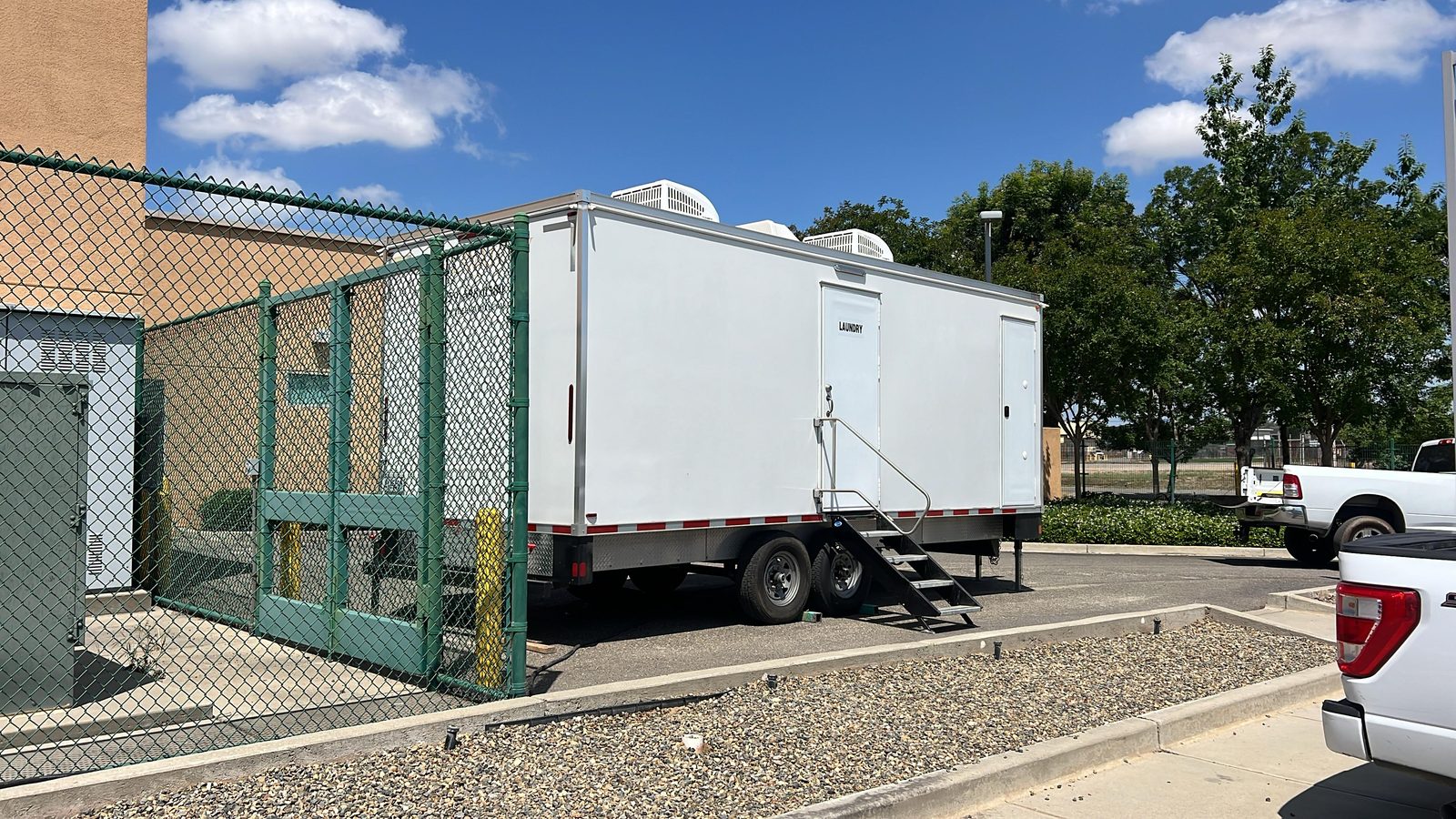 8-station laundry trailer parked along a fenced utility yard at a facility parking lot, The Lavatory NorCal
