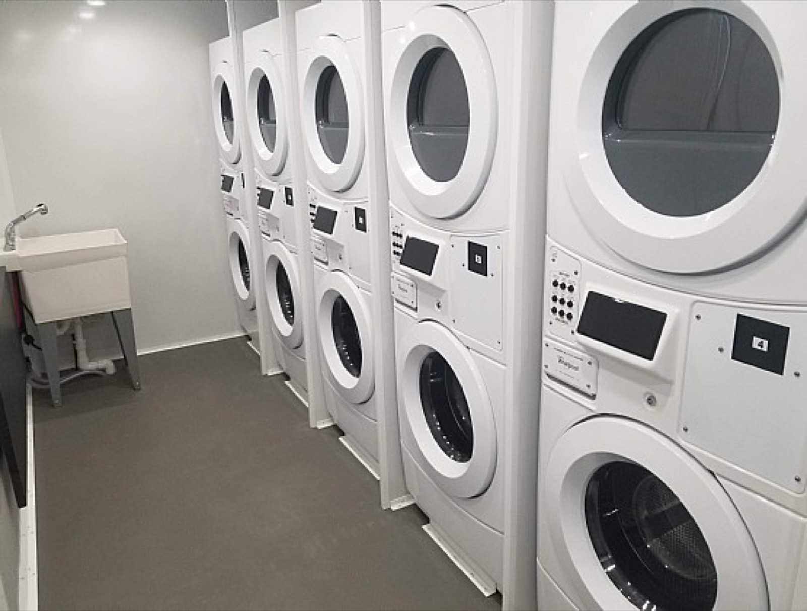Stacked washers and dryers with a utility sink inside a temporary laundry trailer, The Lavatory NorCal