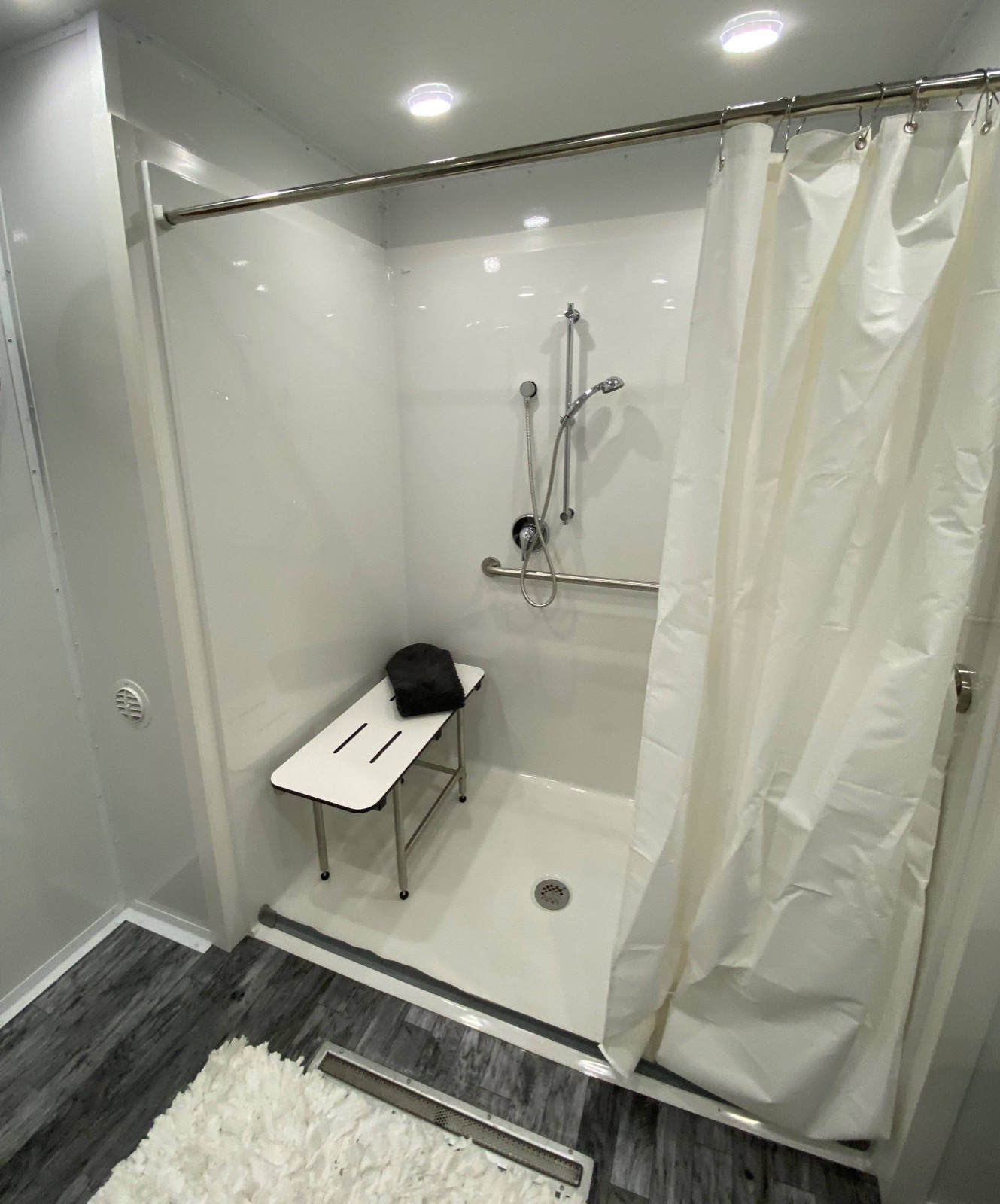 Roll-in accessible shower with a grab bar, handheld sprayer and fold-down bench in a shower trailer, The Lavatory NorCal