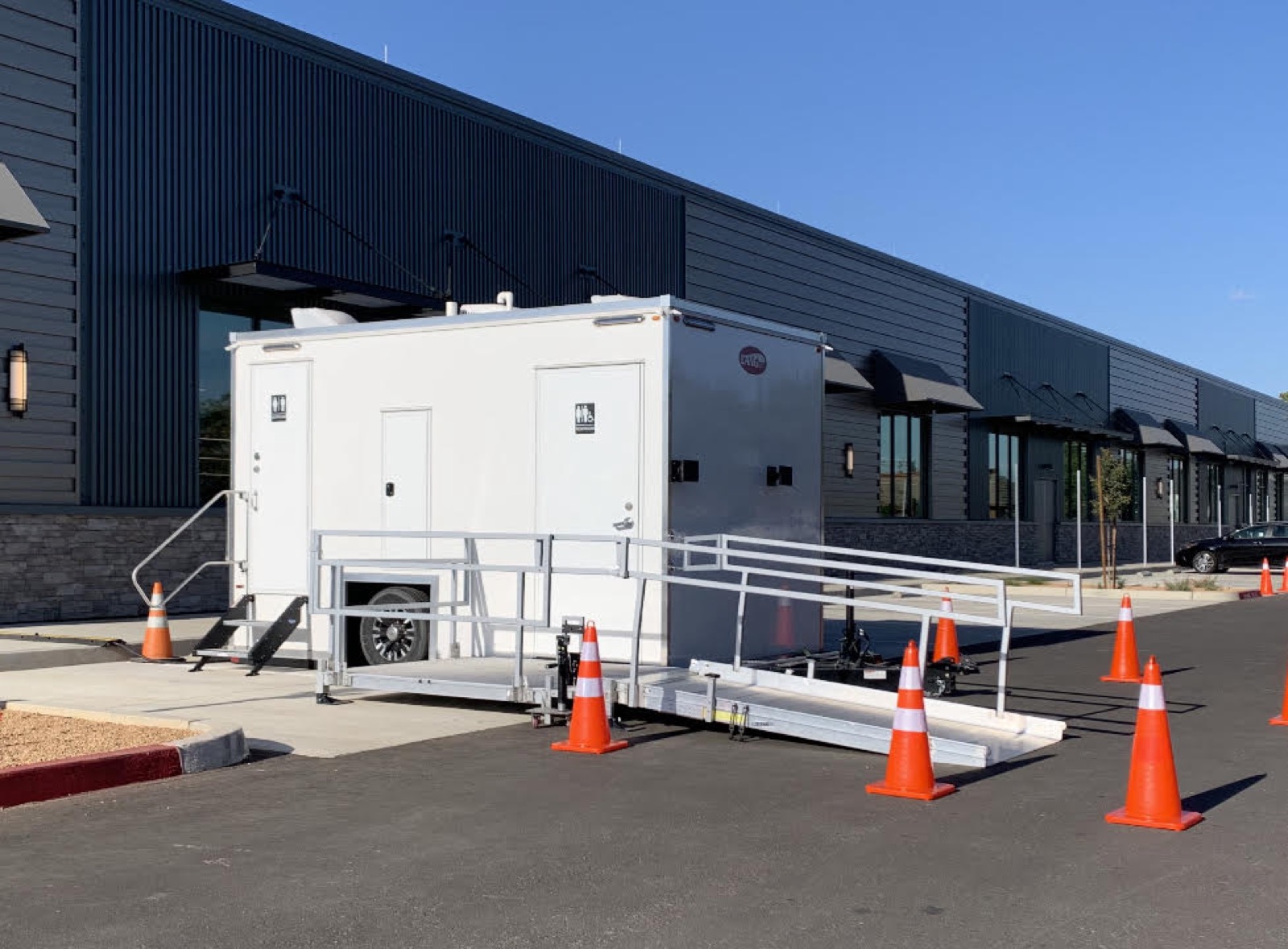 Smaller ADA plus 2 bathroom trailer with an aluminum ramp outside an office building, The Lavatory NorCal