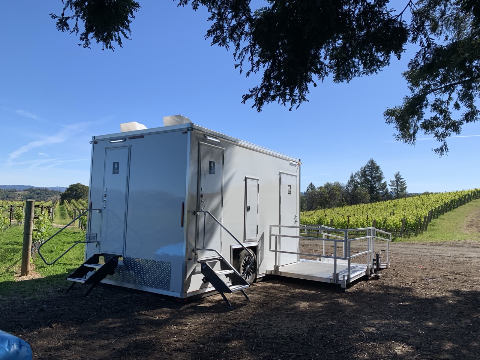 ADA plus 2 bathroom trailer with a platform ramp beside a hillside vineyard, The Lavatory NorCal