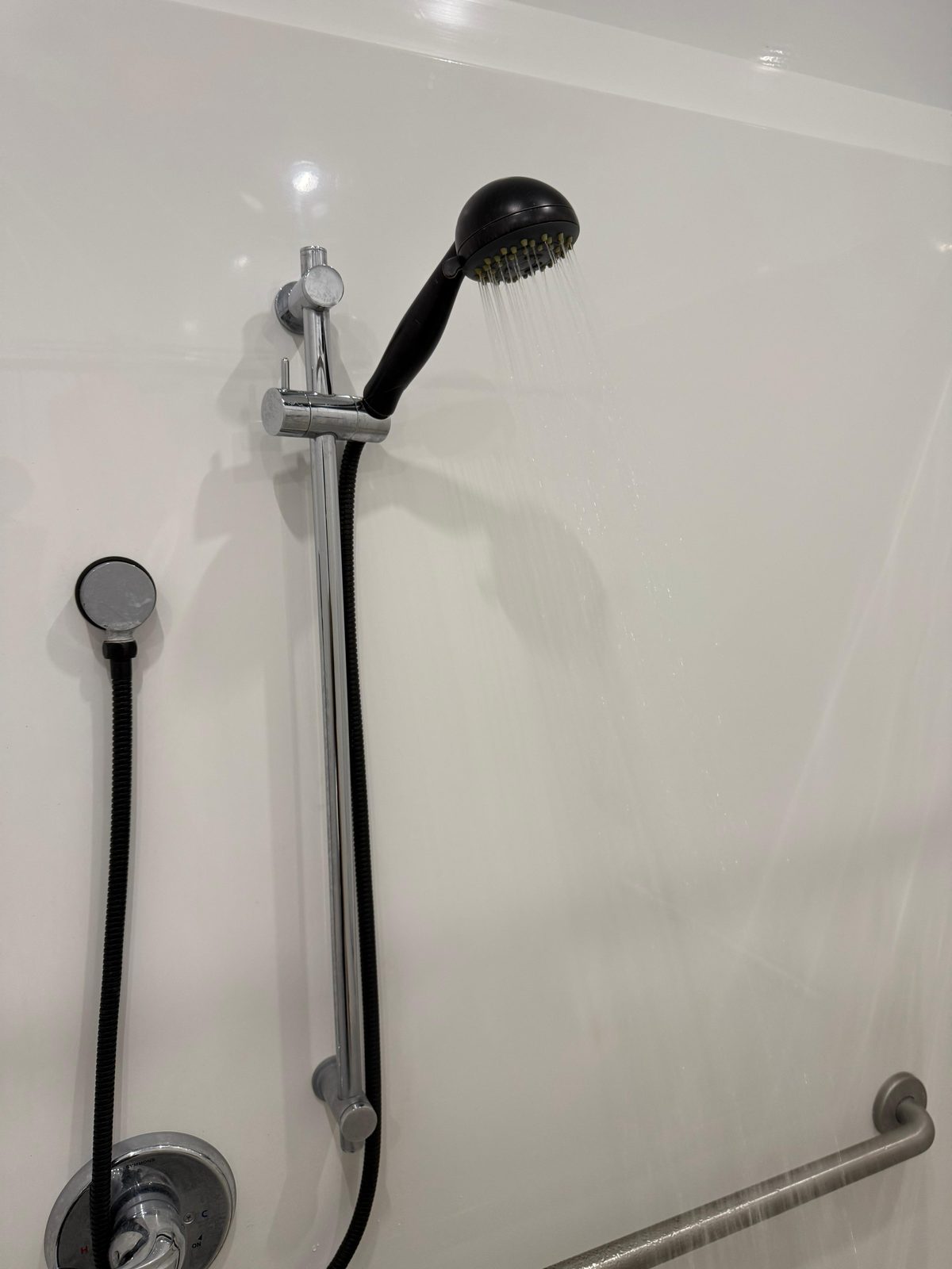 Inside the ADA plus 2 shower trailer: handheld shower on a slide bar with a grab bar, The Lavatory NorCal