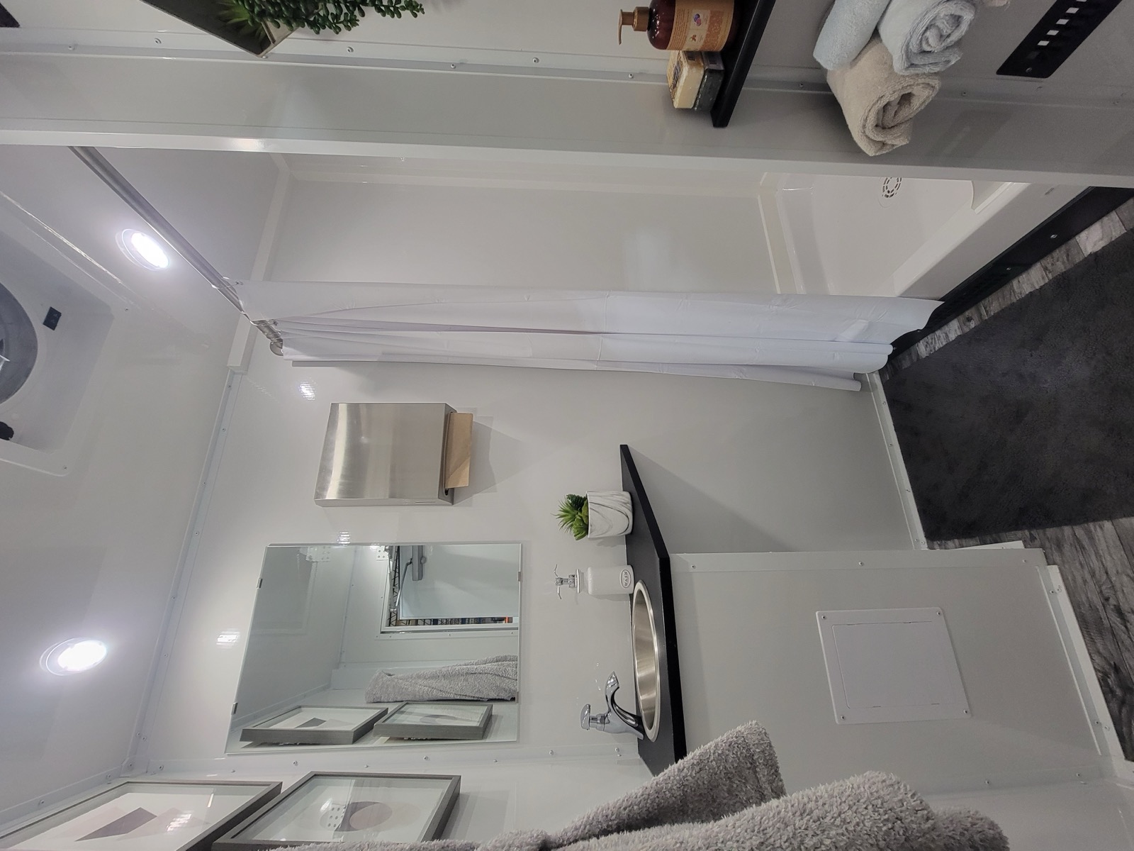 Private shower room with a sink, mirror and folded towels inside a mobile shower trailer, The Lavatory NorCal