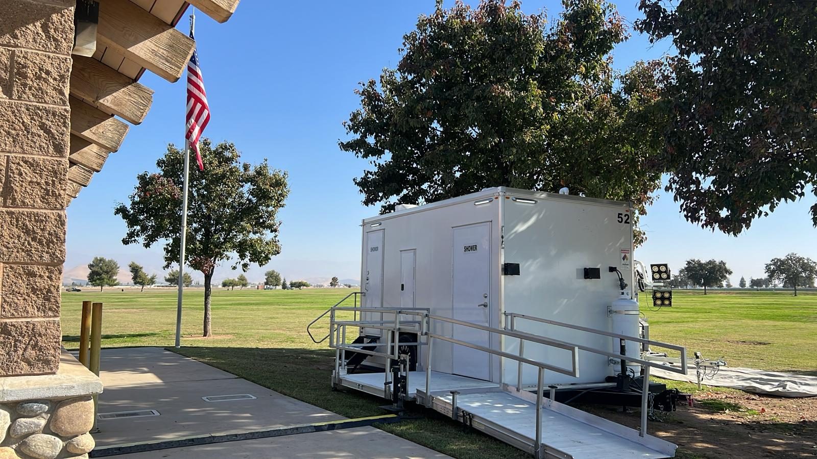 ADA plus 2 shower trailer with an aluminum ramp set up on a park lawn, The Lavatory NorCal