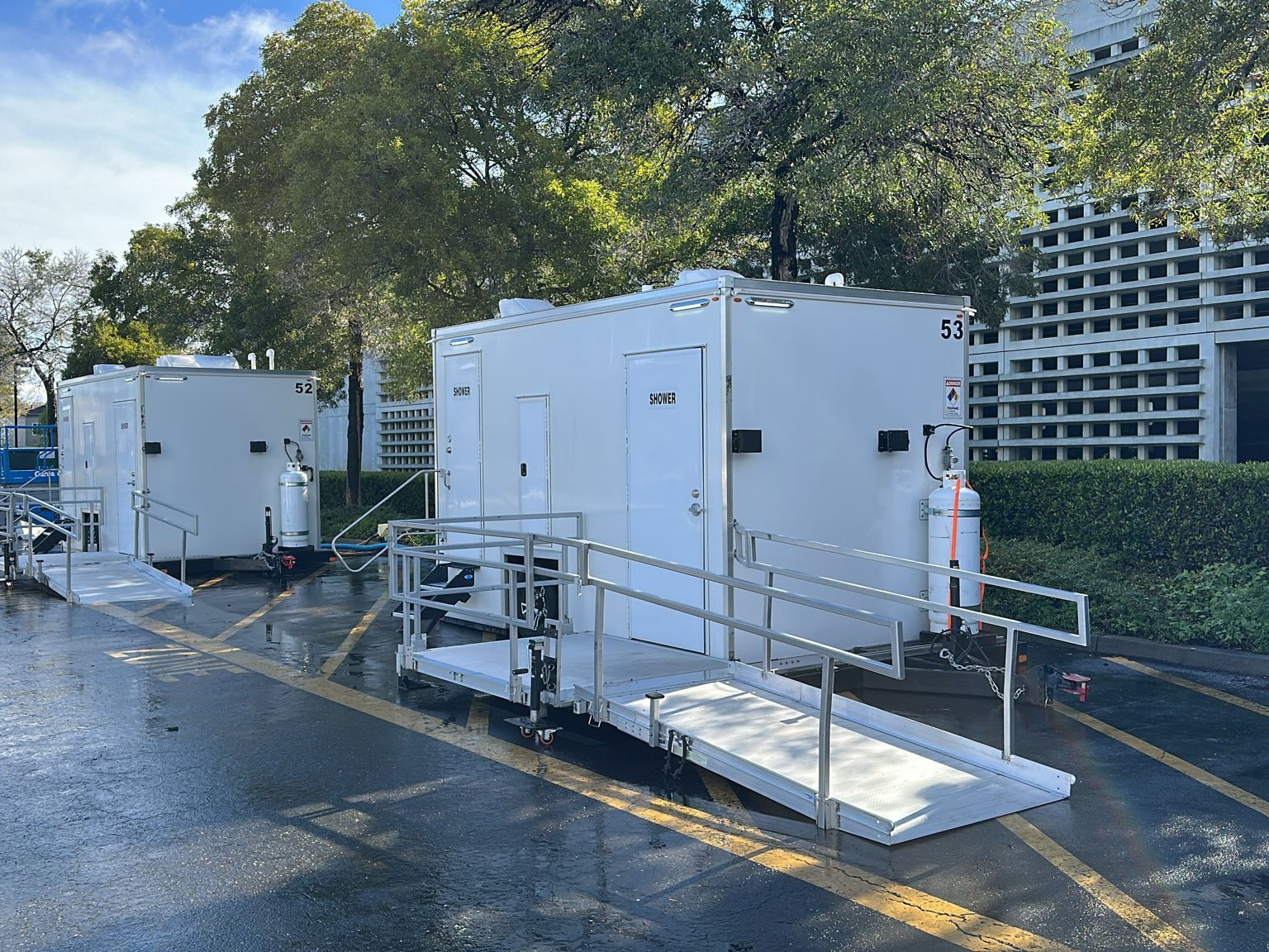 ADA plus 2 shower trailer with a railed ramp platform beside a second shower unit in a parking lot, The Lavatory NorCal
