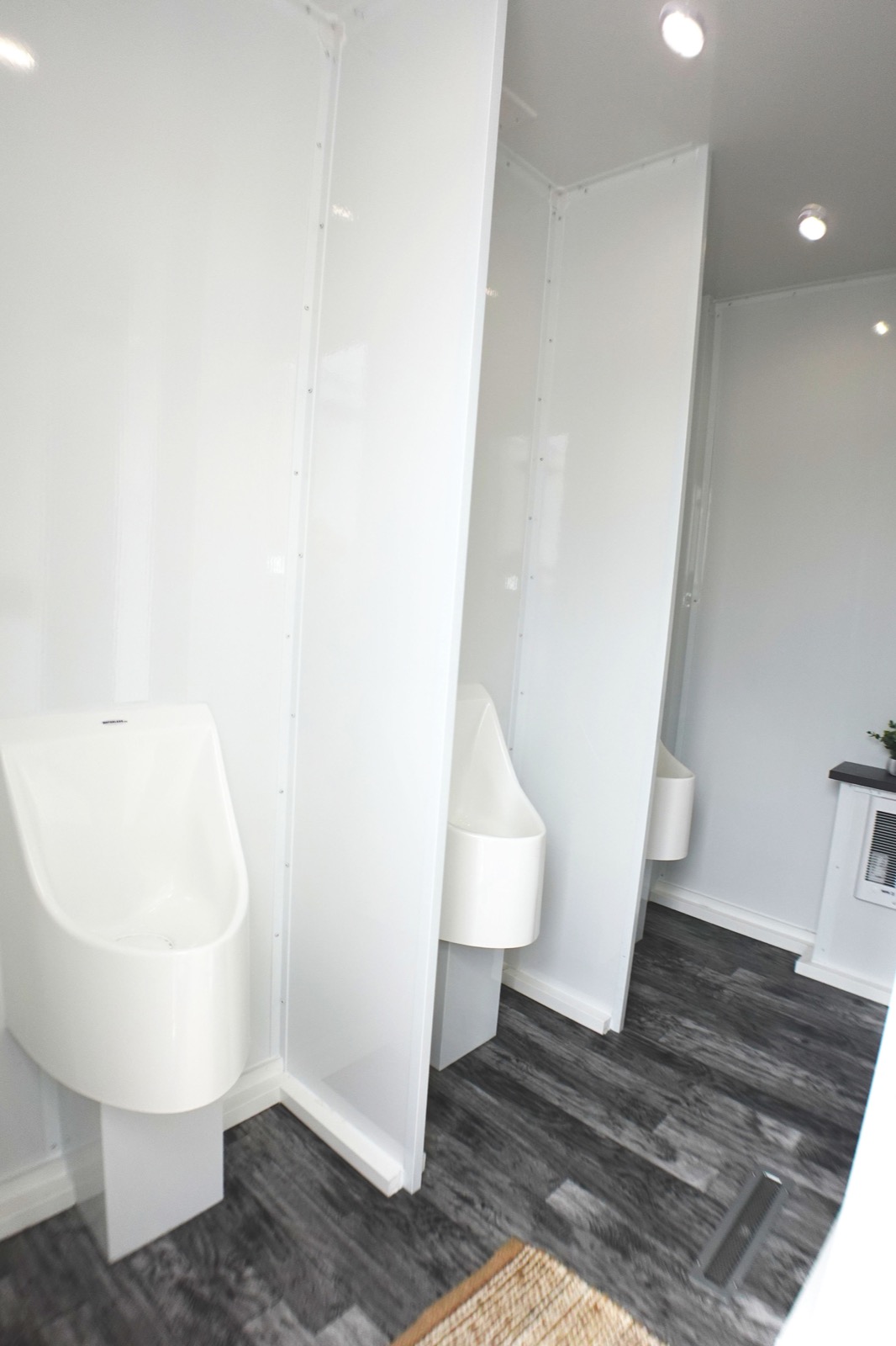 Row of urinals with privacy partitions inside an ADA plus 6 portable bathroom trailer used on job sites, The Lavatory NorCal