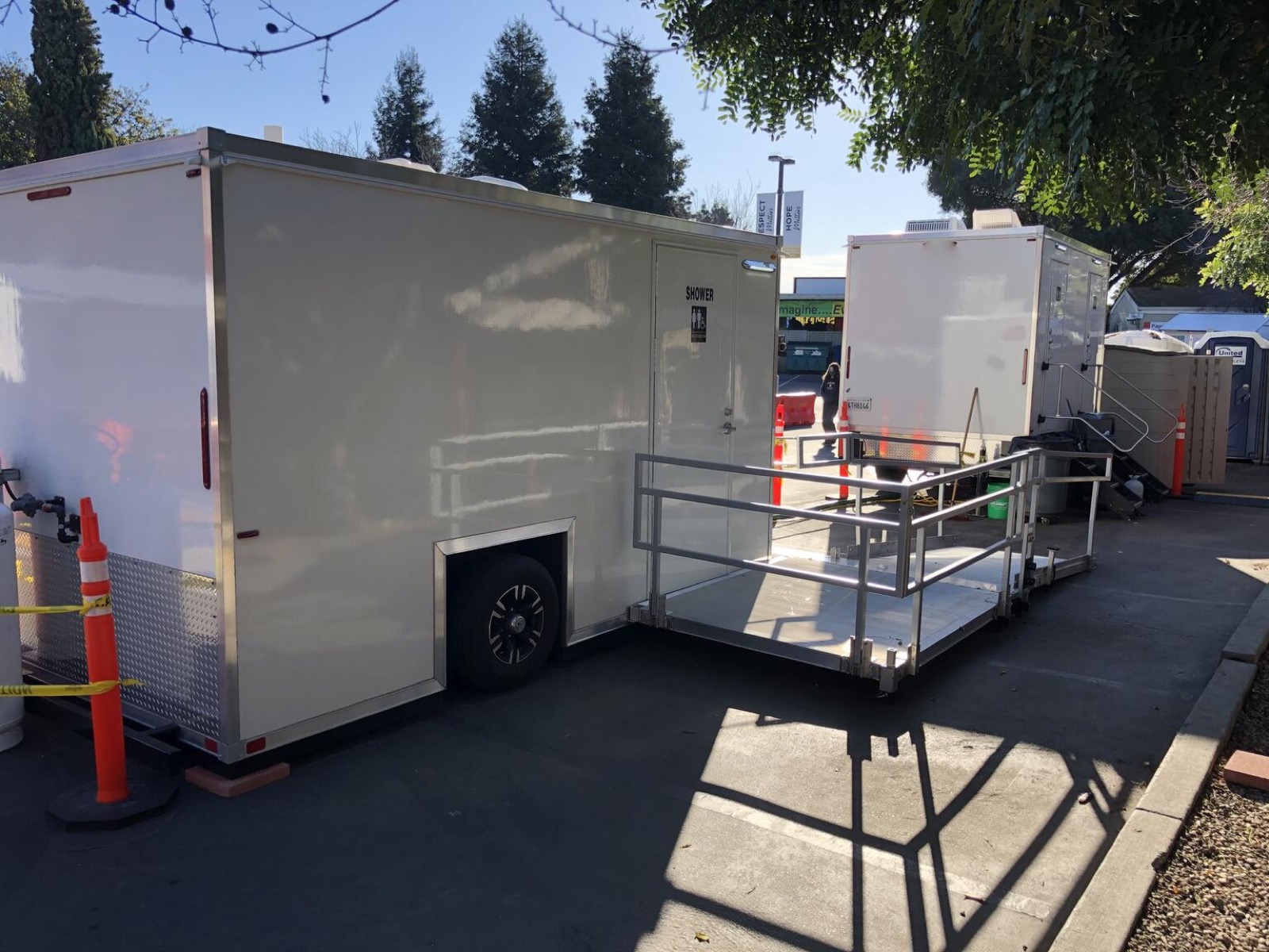 Accessible restroom trailer with a platform and railed ramp set up at a city site, The Lavatory NorCal