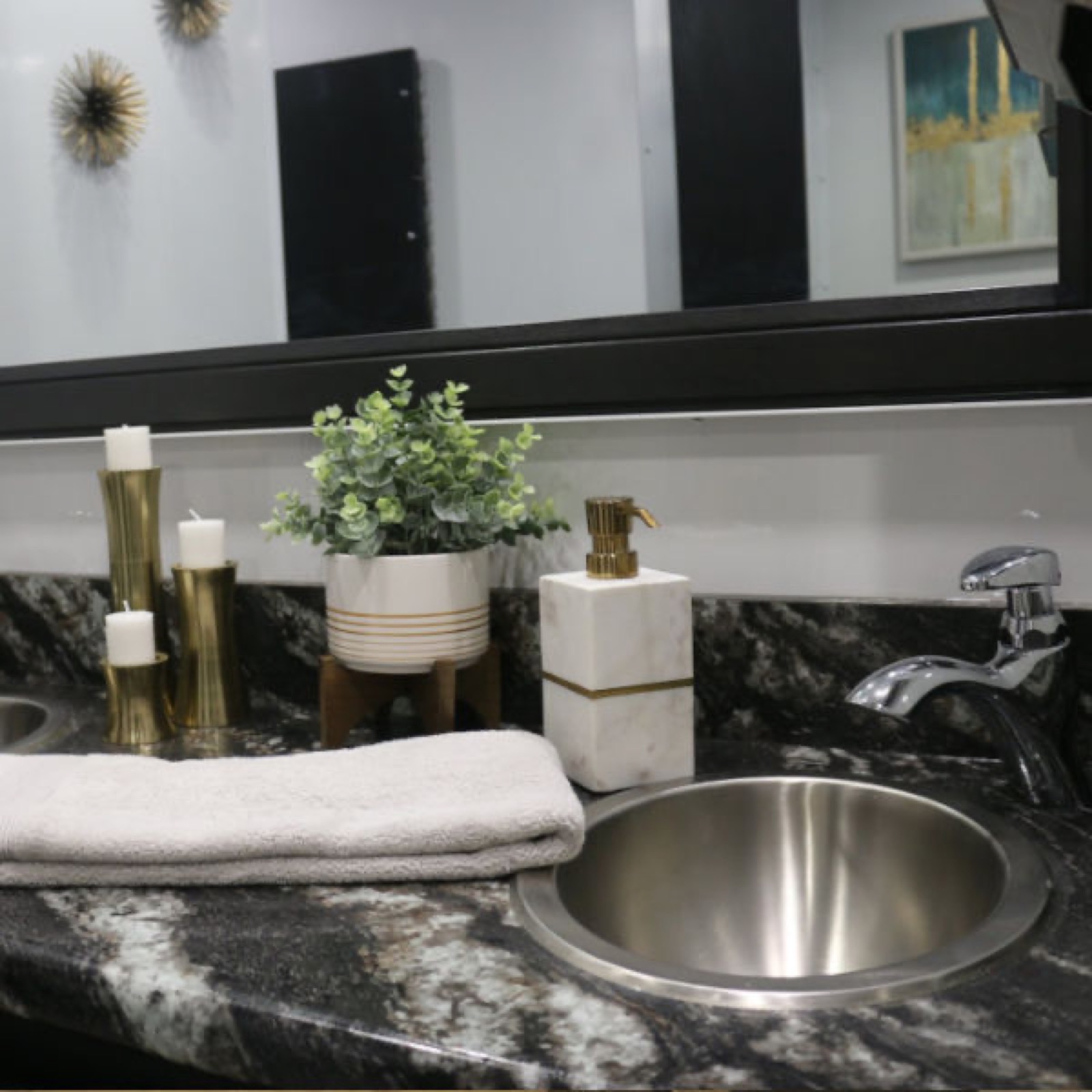 Granite vanity with a steel sink, a plant and gold candle holders inside a luxury restroom trailer, The Lavatory NorCal