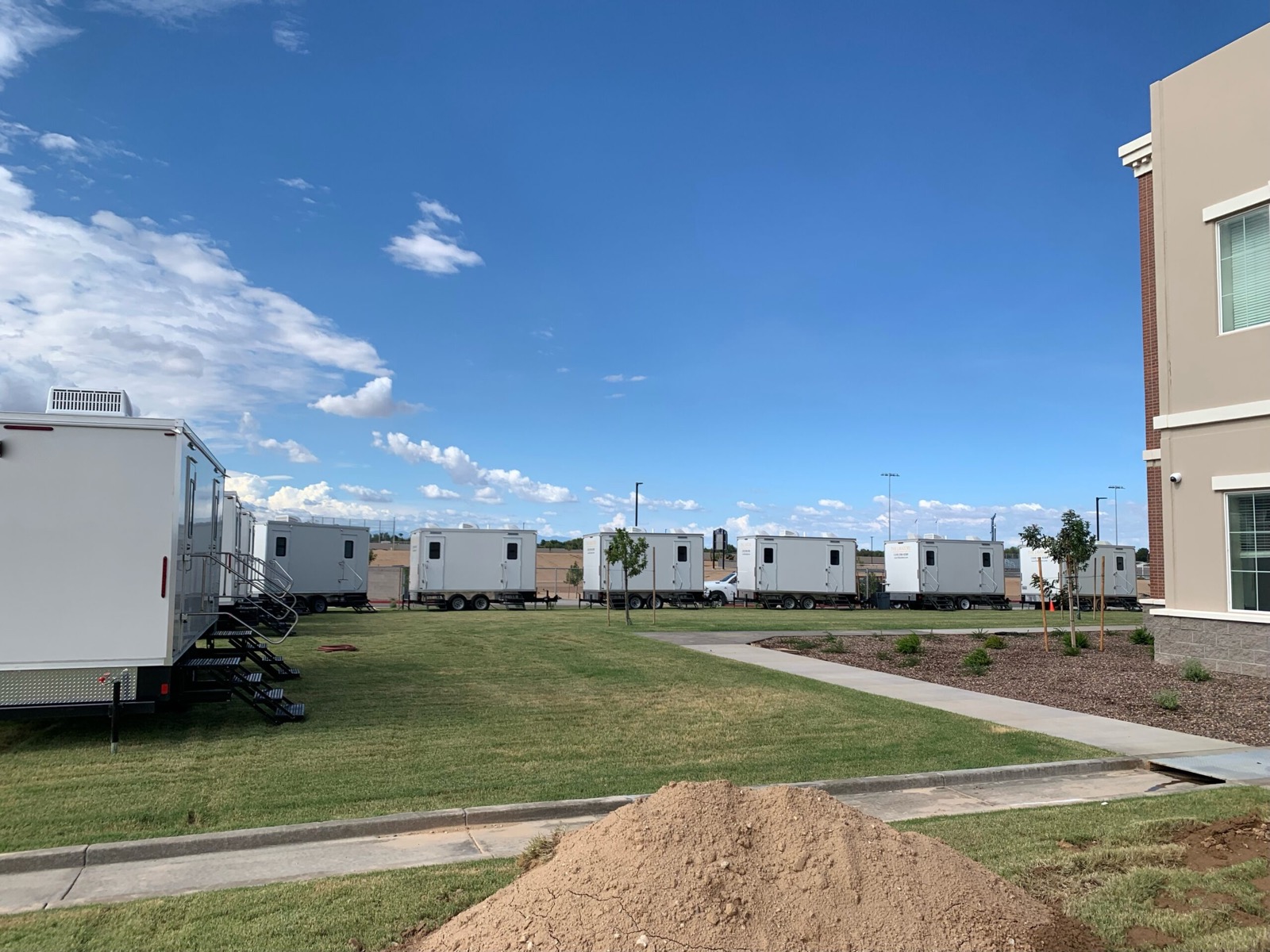 Row of portable restroom trailers lined up on the lawn of a new school campus, The Lavatory NorCal