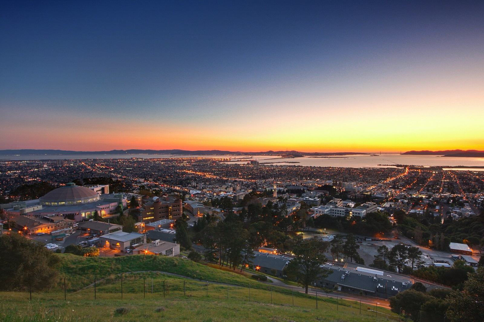 View at dusk from the Berkeley Hills over the campus, the city lights and the bay, where The Lavatory NorCal delivers restroom trailers