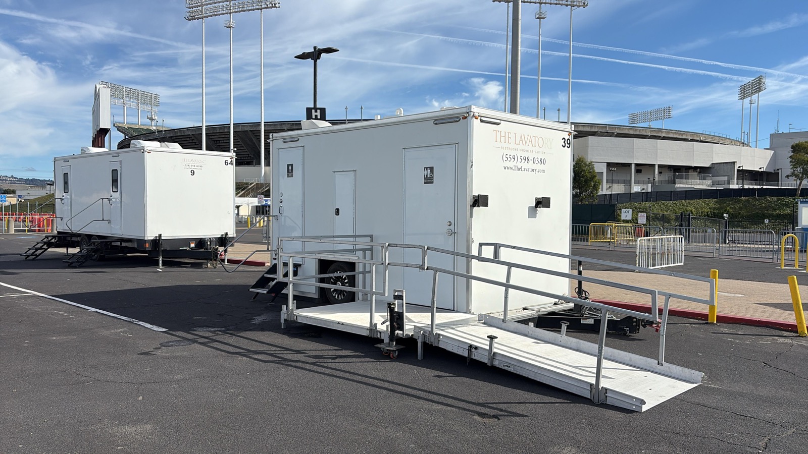 ADA plus 2 bathroom trailer with an aluminum ramp in front of a 9-stall unit in a stadium parking lot in Oakland, near Berkeley, The Lavatory NorCal