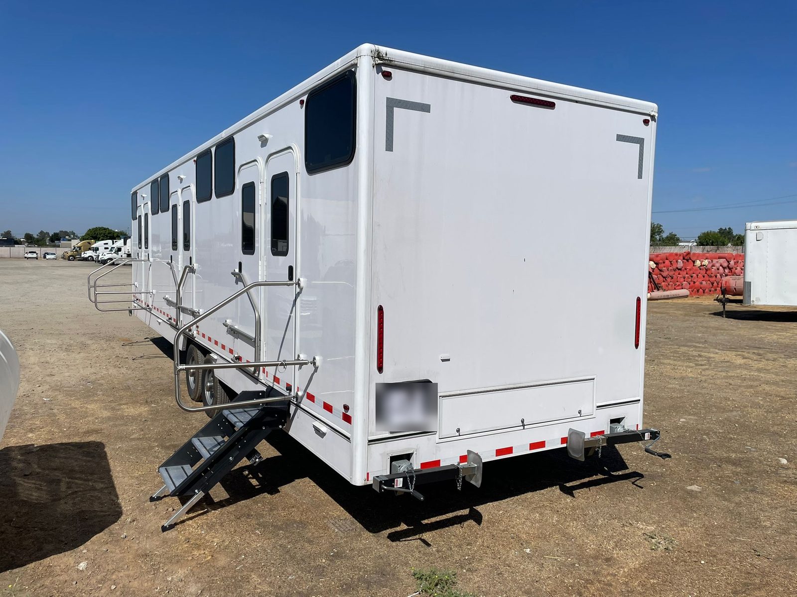 12-station bunkhouse sleeper trailer, rear three-quarter view showing bunk doors with steps and windows along the side, The Lavatory NorCal