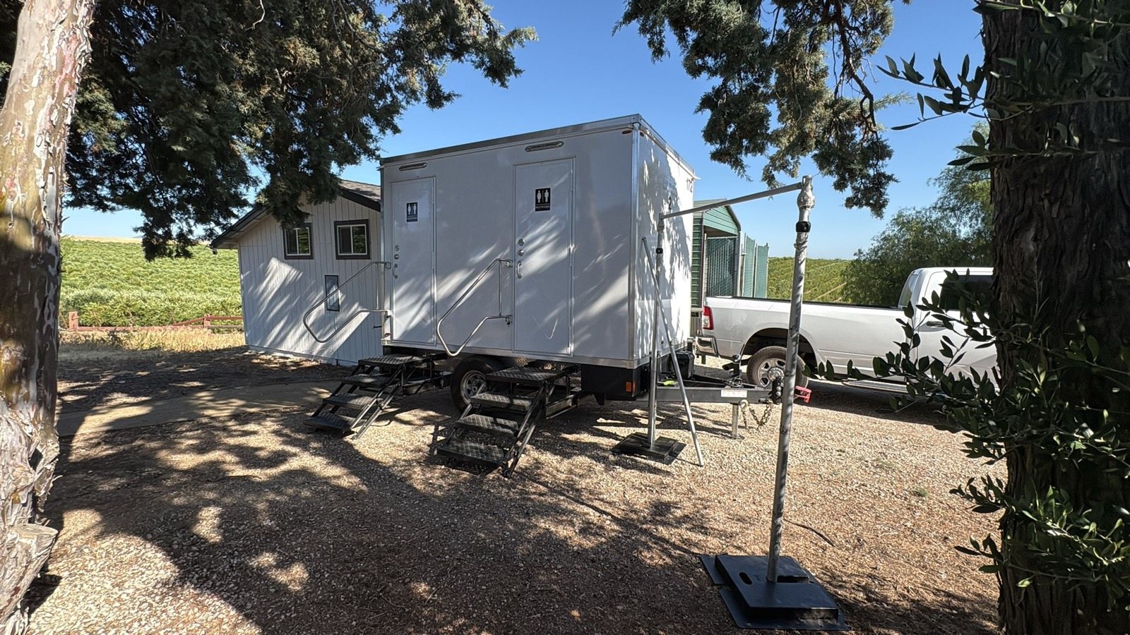 2-stall restroom trailer on gravel under trees beside a vineyard in Byron, East Contra Costa, The Lavatory NorCal