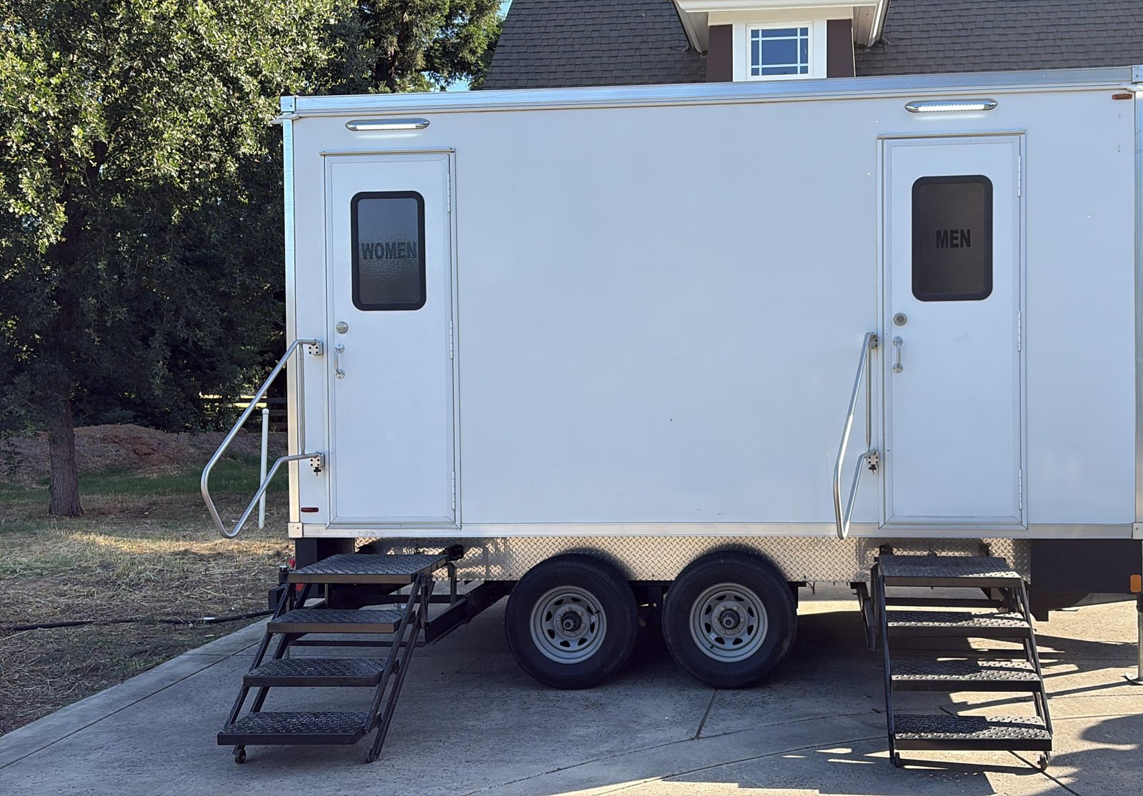 5-stall luxury bathroom trailer with women's and men's doors and steel steps on an Elk Grove estate driveway, The Lavatory NorCal