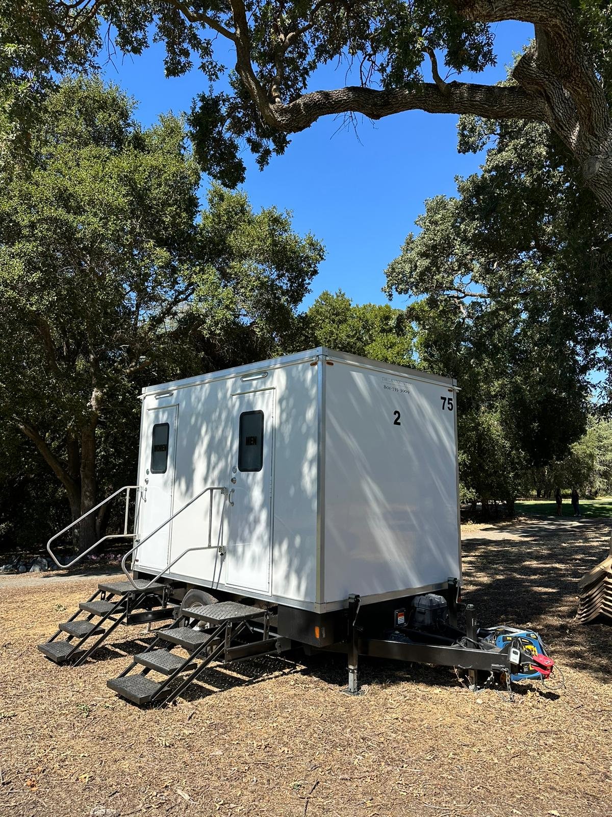 2-stall bathroom trailer with a generator under a big oak at a Livermore park event, The Lavatory NorCal