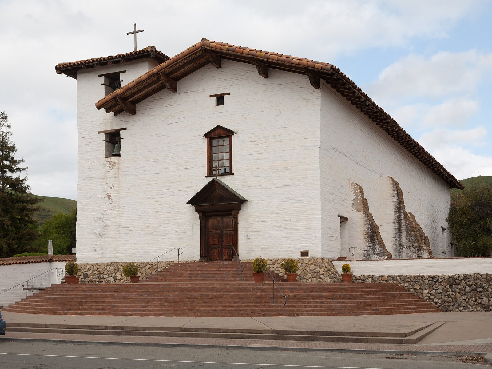 Whitewashed adobe church of Mission San Jose in Fremont with its bell tower and brick steps, an area The Lavatory NorCal serves