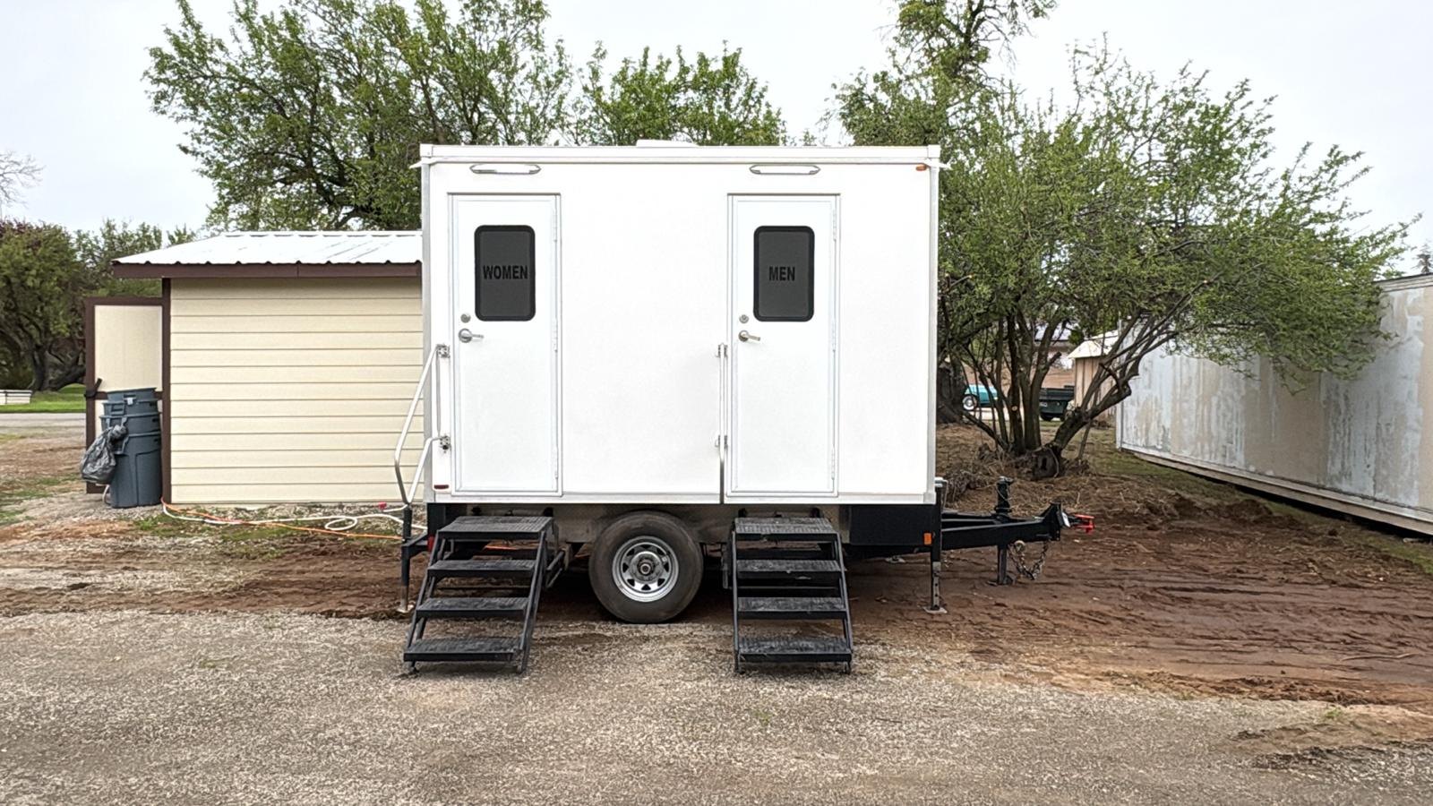 2-stall bathroom trailer with women's and men's doors on a gravel and dirt lot in Roseville, The Lavatory NorCal