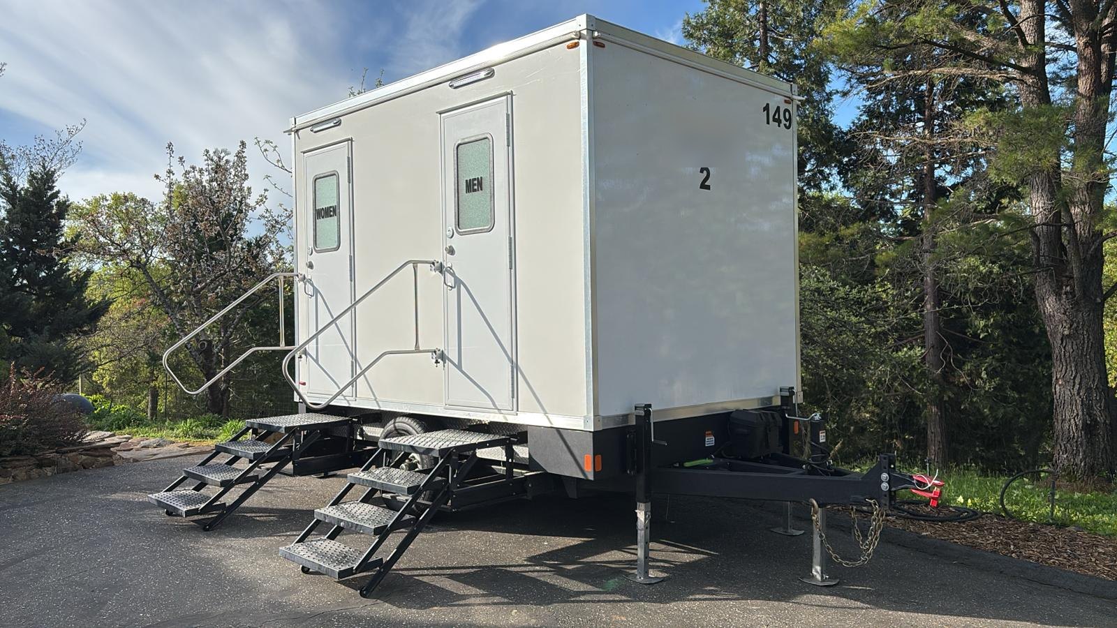 2-stall luxury bathroom trailer with steel stairs and handrails on a paved drive among pines in the Placer County foothills near Roseville, The Lavatory NorCal