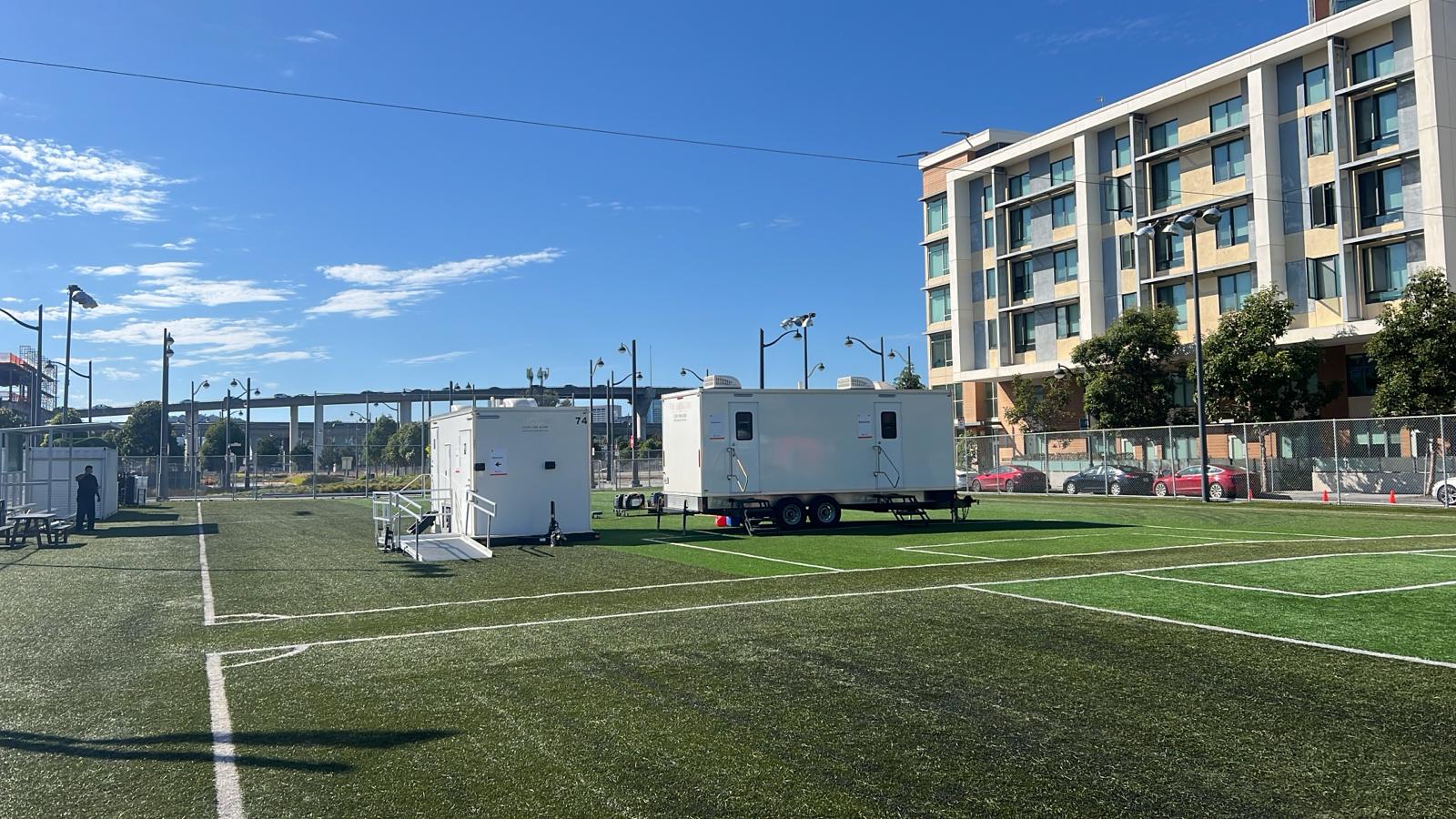 9-stall restroom trailer and an accessible unit with a ramp on an artificial turf field in Mission Bay beside the freeway, The Lavatory NorCal