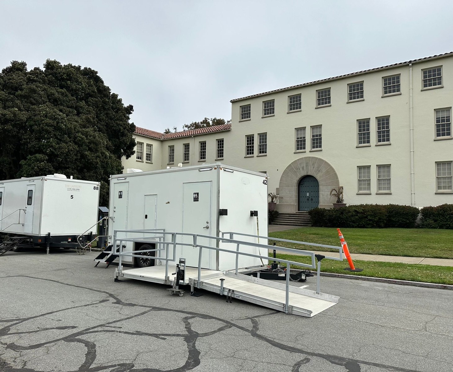 5-stall bathroom trailer next to an accessible unit with a railed ramp in front of a historic building in the Presidio, The Lavatory NorCal