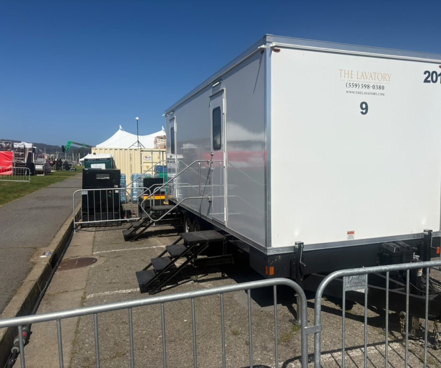 9-stall luxury restroom trailer with two entry stairs behind crowd barricades at the Escape from Alcatraz Triathlon staging area in San Francisco, The Lavatory NorCal
