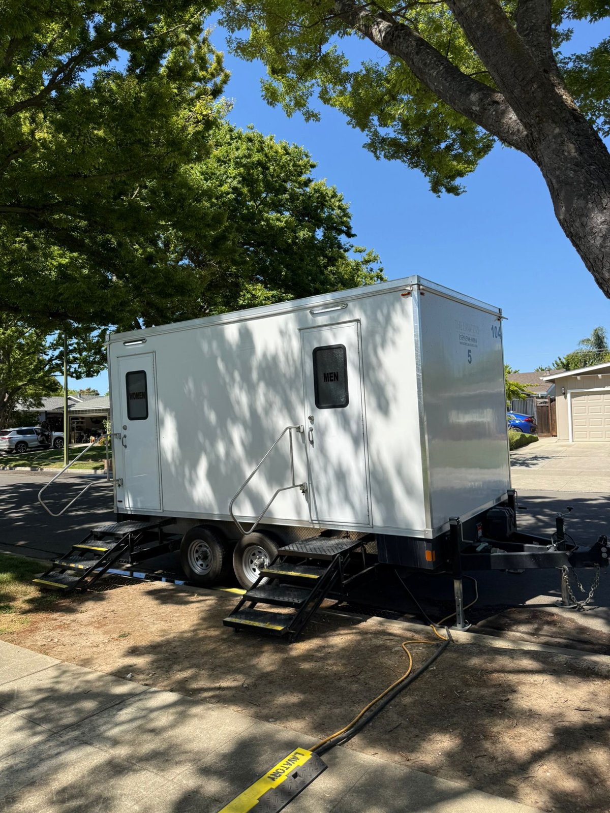 5-stall bathroom trailer parked under shade trees on a residential San Jose street, The Lavatory NorCal