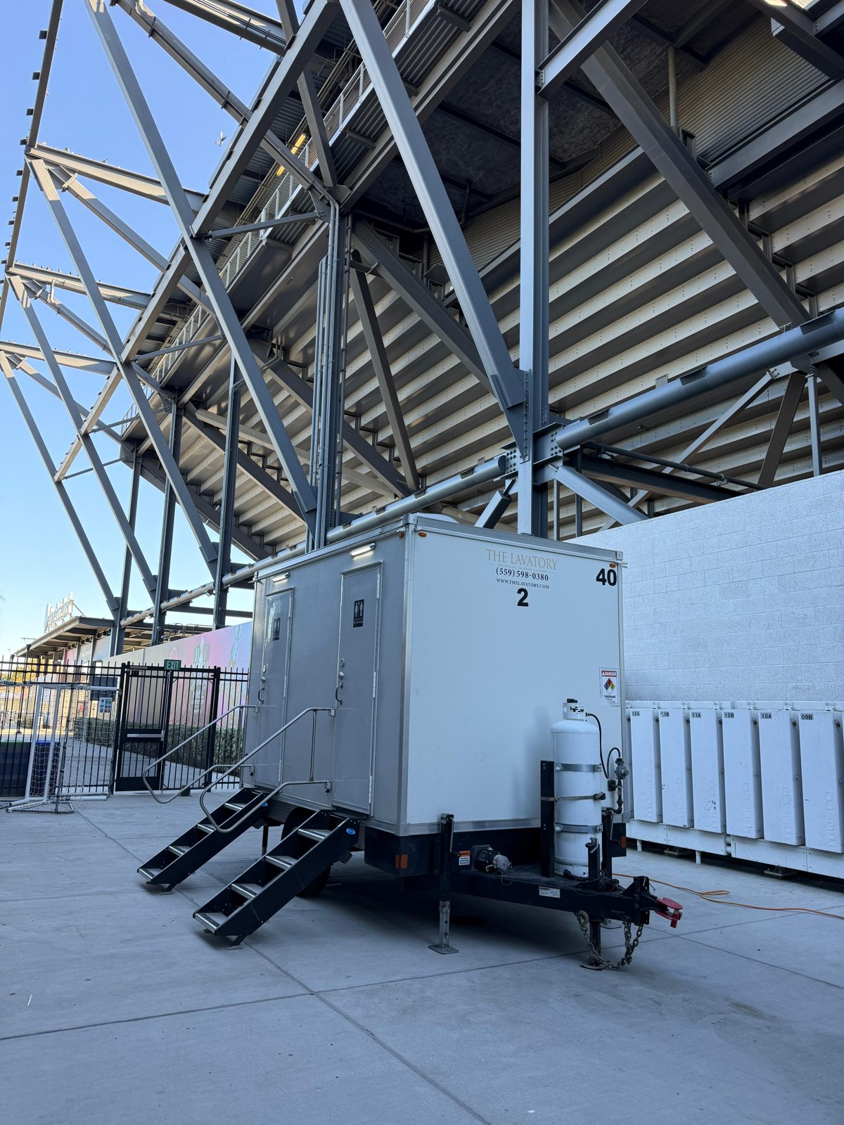 Compact restroom trailer with folding stairs set on the concourse under the grandstand at a San Jose soccer stadium, The Lavatory NorCal