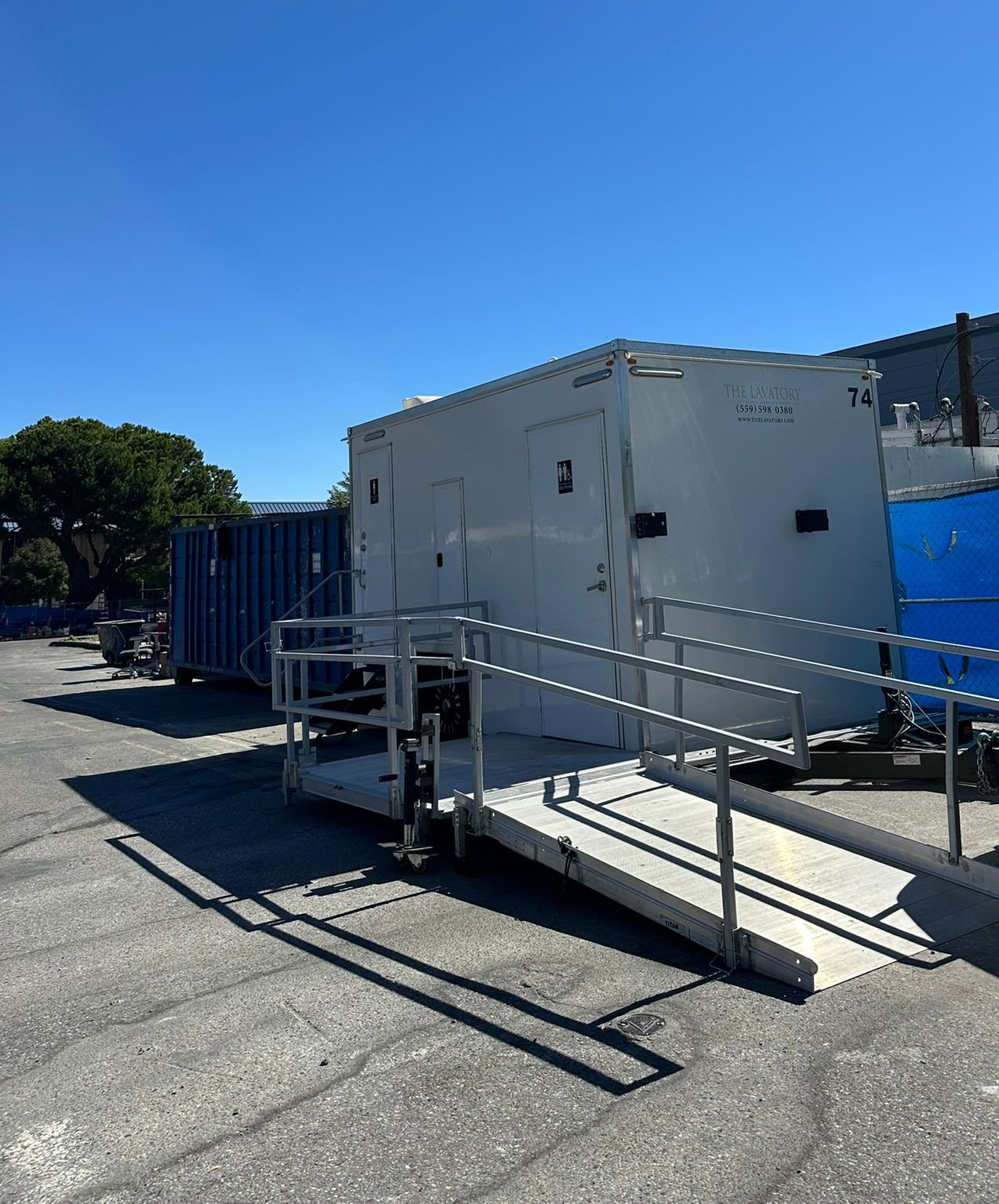 ADA plus 2 restroom trailer with a railed ramp in a paved industrial yard, The Lavatory NorCal